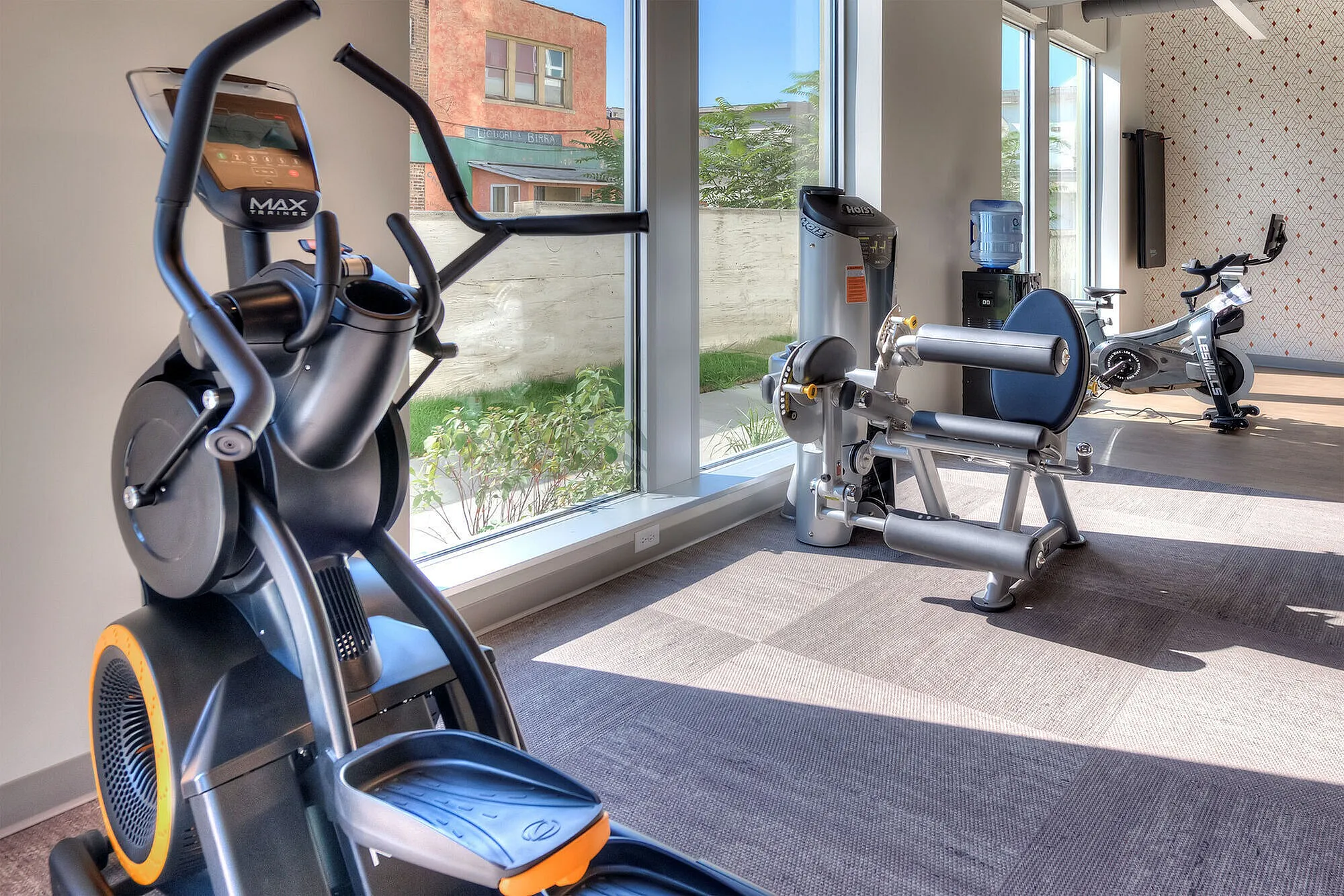 Bright and modern gym with state-of-the-art exercise equipment, featuring cardio machines and strength training stations.