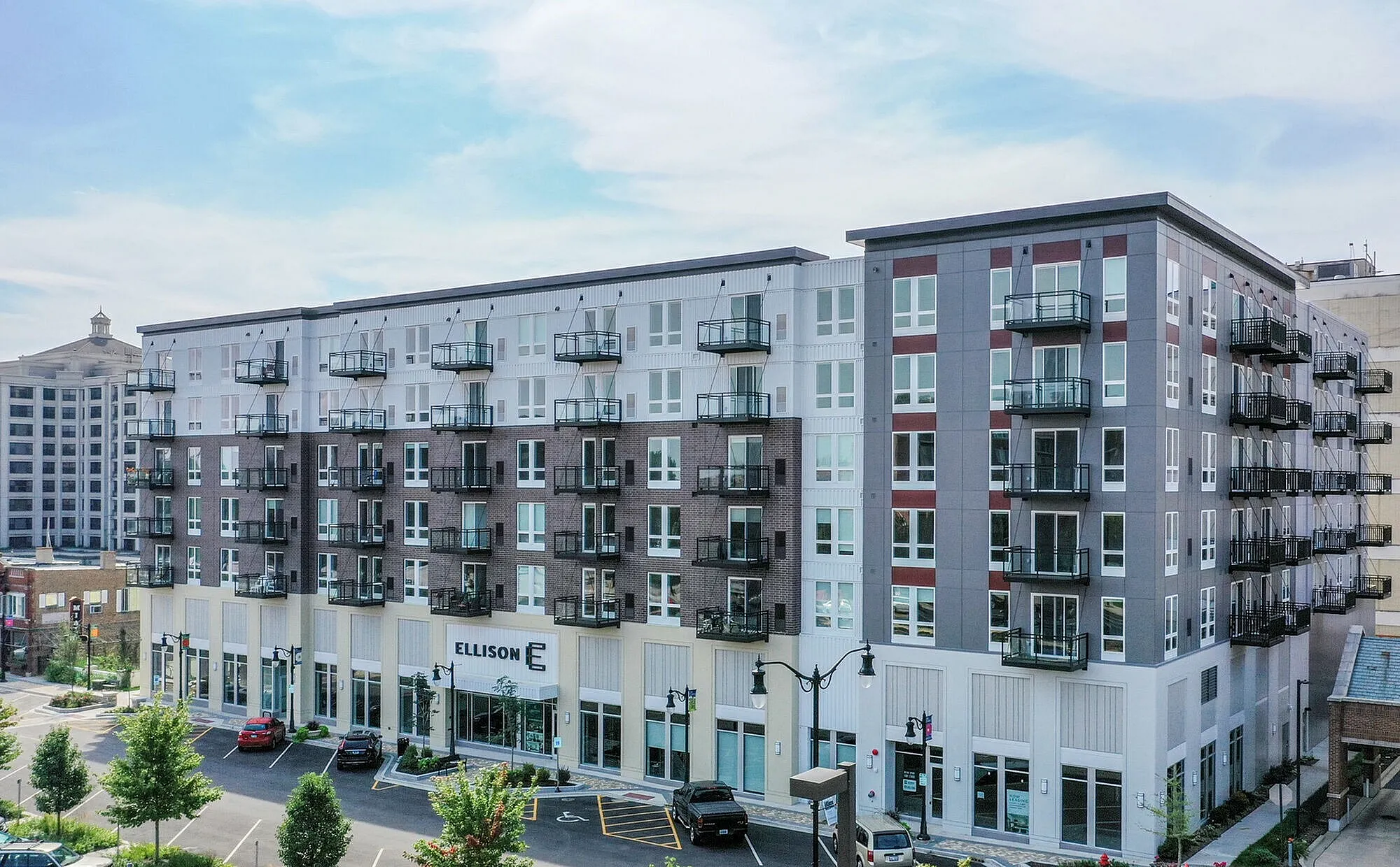 Contemporary six-story apartment building with modern facade and multiple balconies, set in a vibrant urban neighborhood.