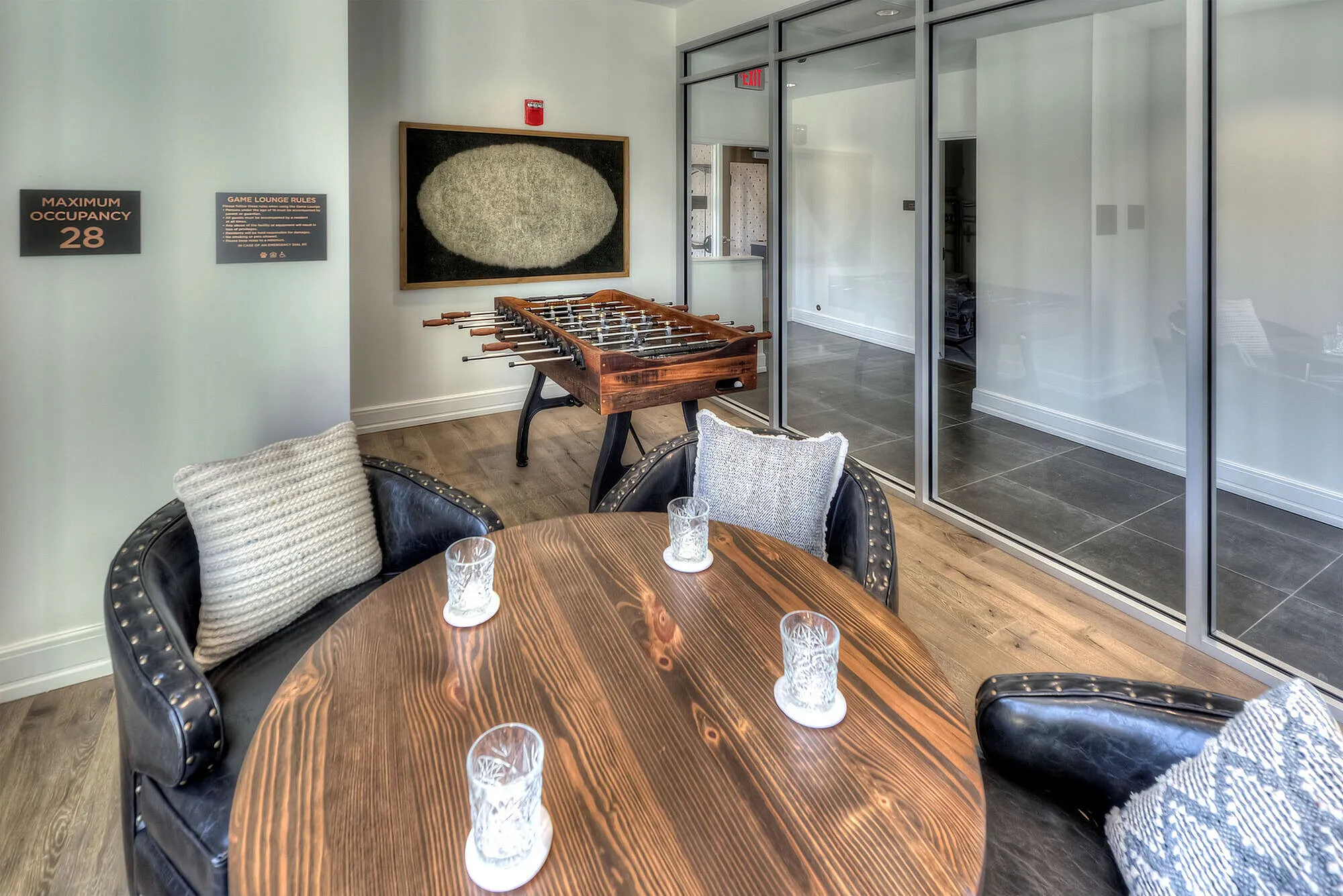 Stylish lounge area featuring a foosball table, elegant round table with crystal glassware, and cozy seating with plush cushions, perfect for relaxation and entertainment.