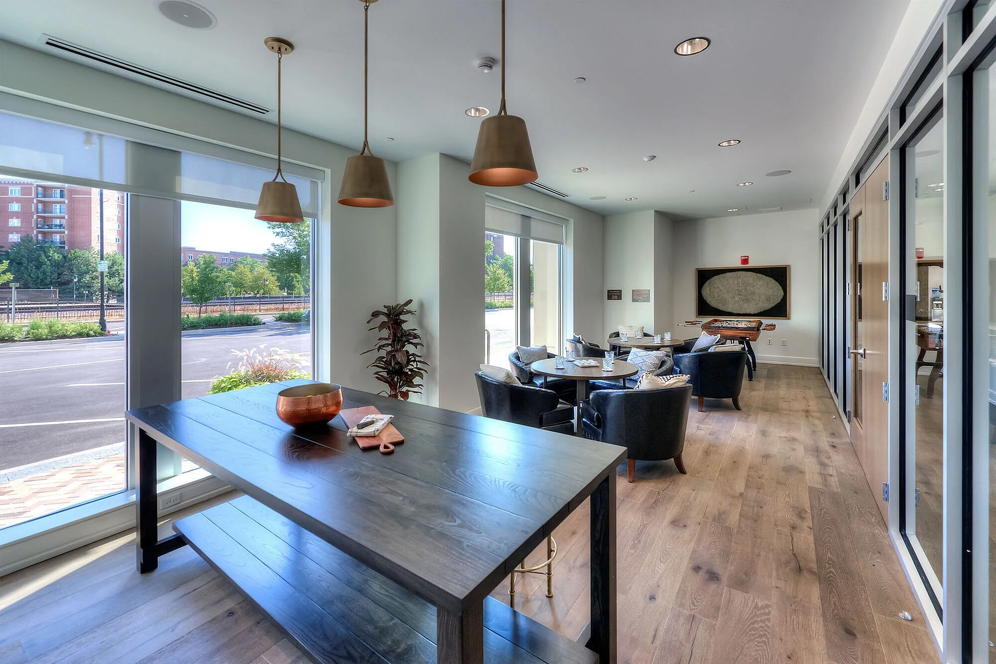 Modern apartment lounge with large windows, natural light, and stylish seating creating a welcoming and sophisticated atmosphere.