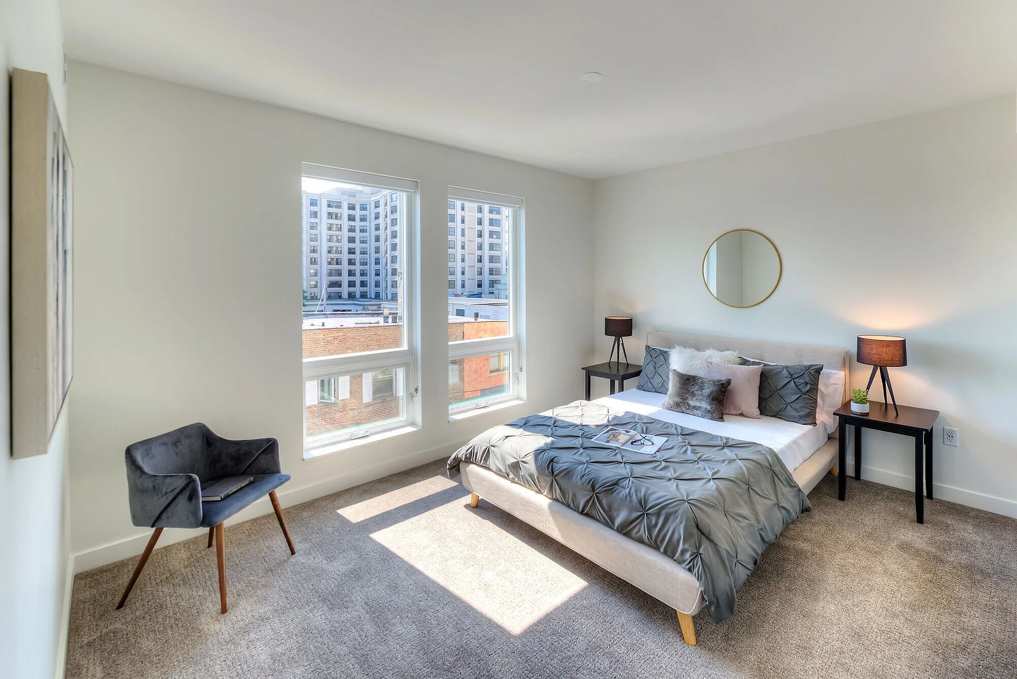 Bright and modern bedroom with large windows, stylish decor, and city views. Cozy ambiance perfect for relaxation.