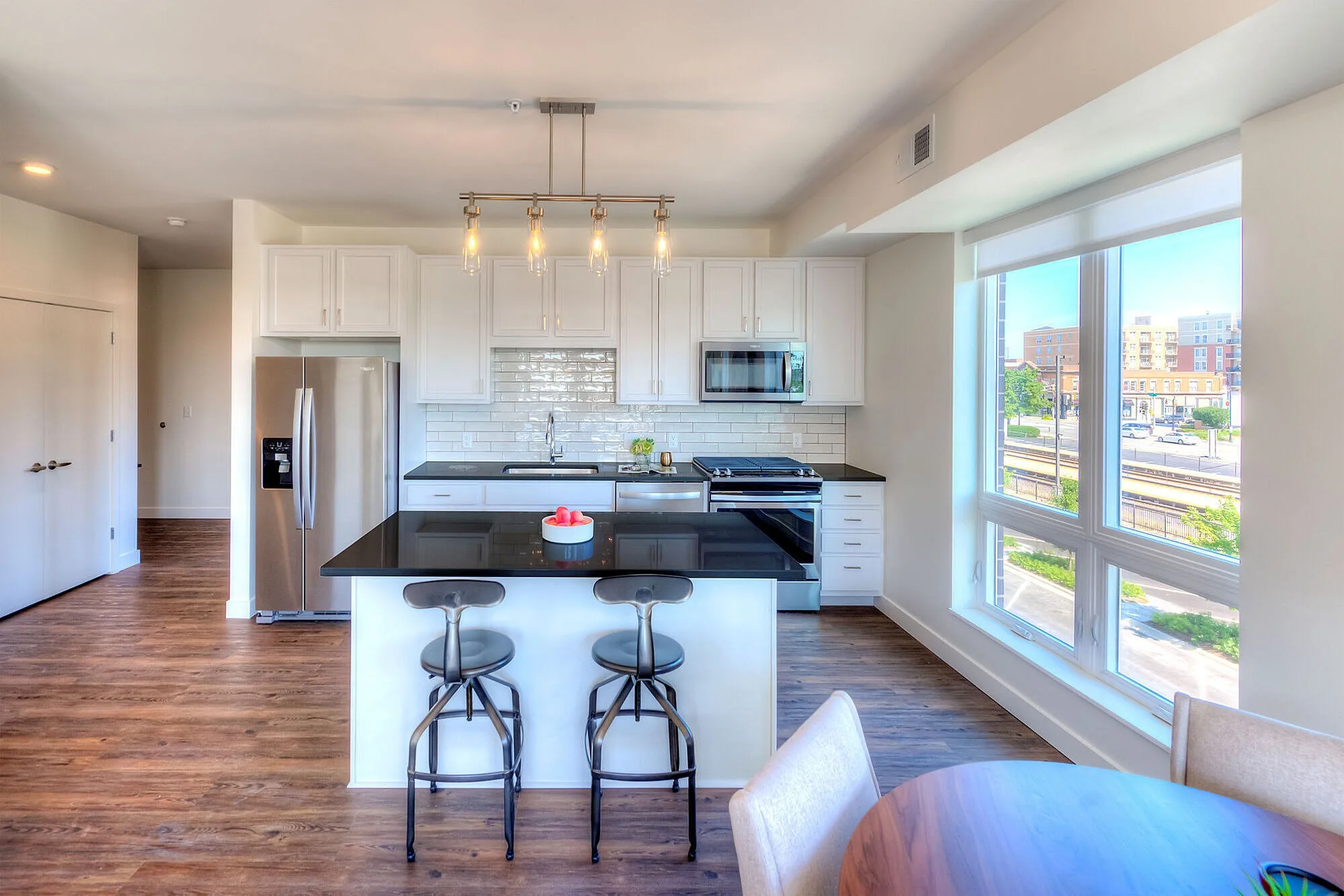 Chic modern kitchen featuring sleek black countertops, stainless steel appliances, and generous natural light through large windows.