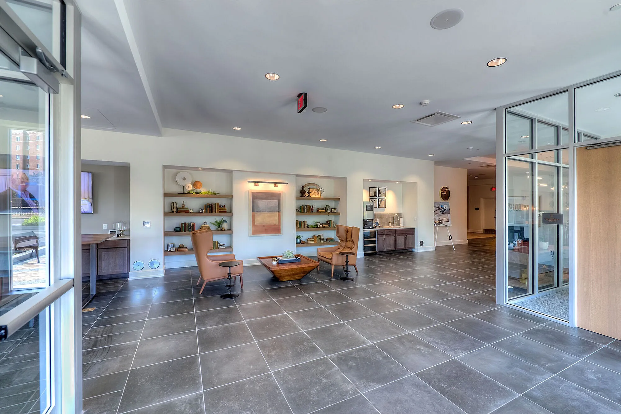 Spacious and modern lobby featuring elegant seating, stylish bookshelves, and contemporary decor with natural light streaming in.
