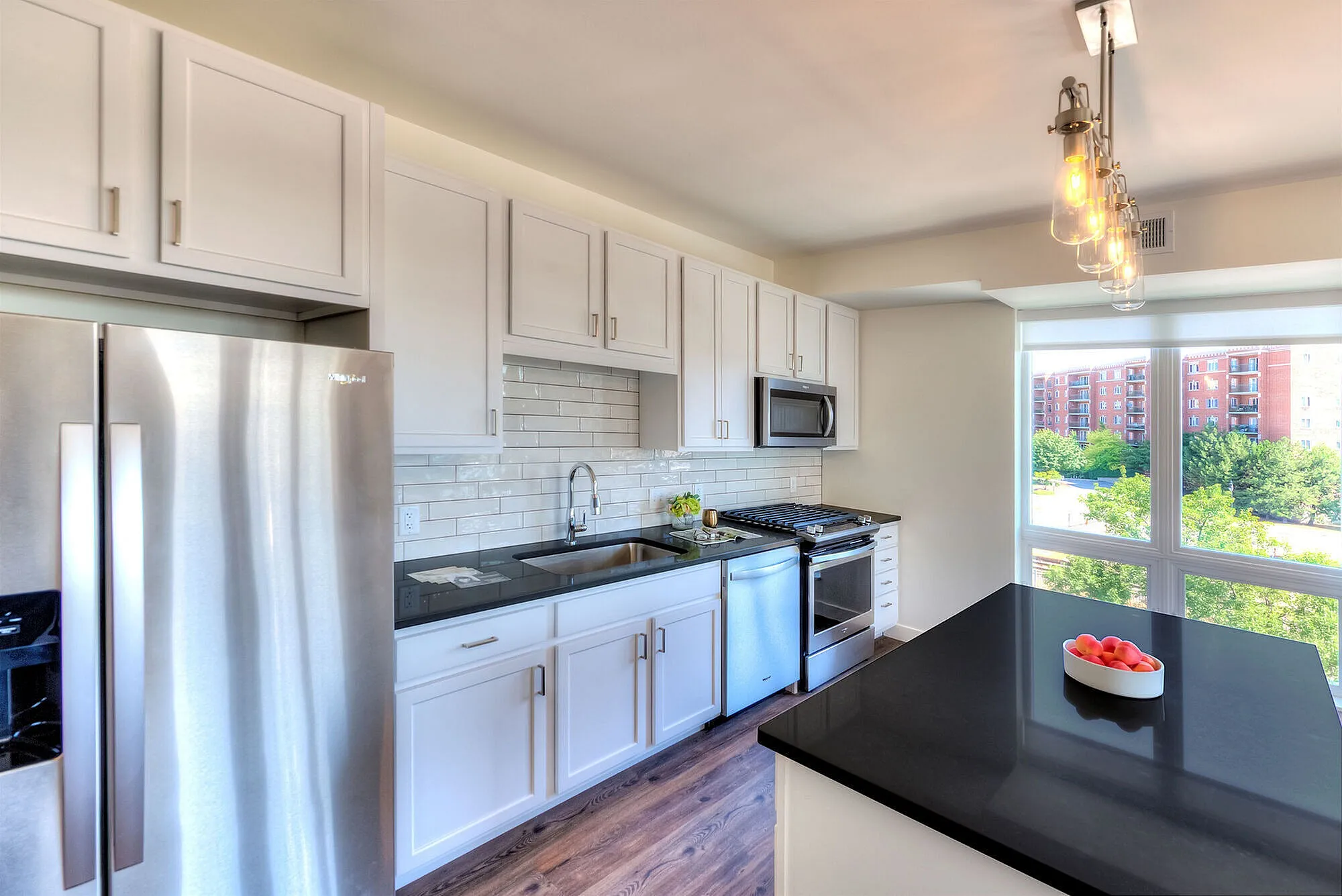 Modern kitchen with sleek stainless steel appliances, white cabinetry, and a large window flooding the space with natural light.