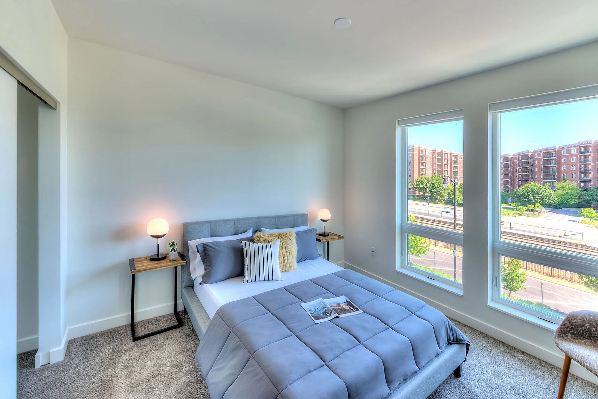 Bright and cozy bedroom with a modern bed, stylish side tables, and large windows offering a stunning city view.