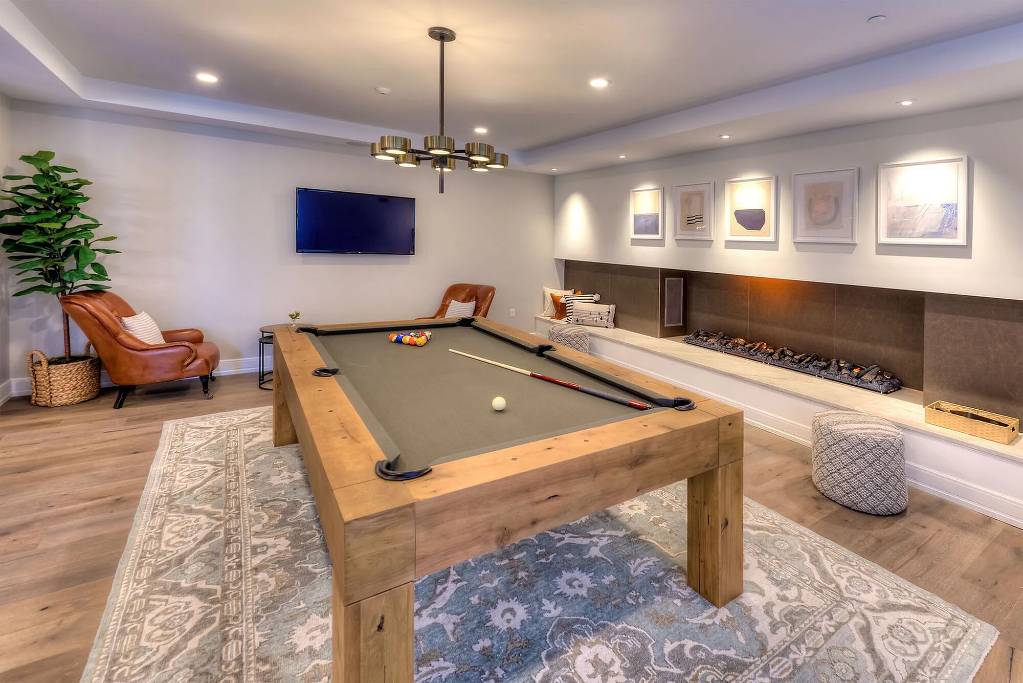 Elegant game room with a stylish pool table, cozy seating, modern wall art, and ambient lighting.