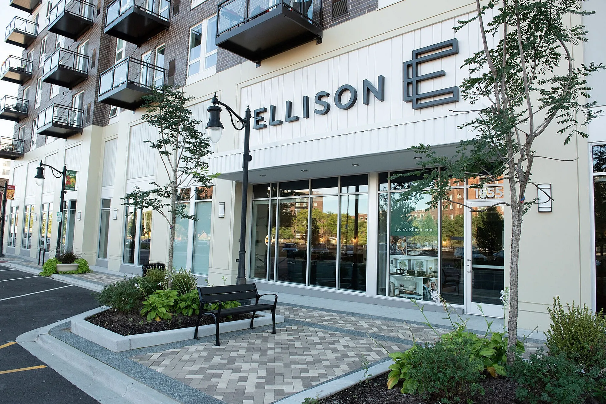 Chic urban residential entrance with modern architecture and inviting landscaping at Ellison. Stylish balconies overlook a well-designed public space.