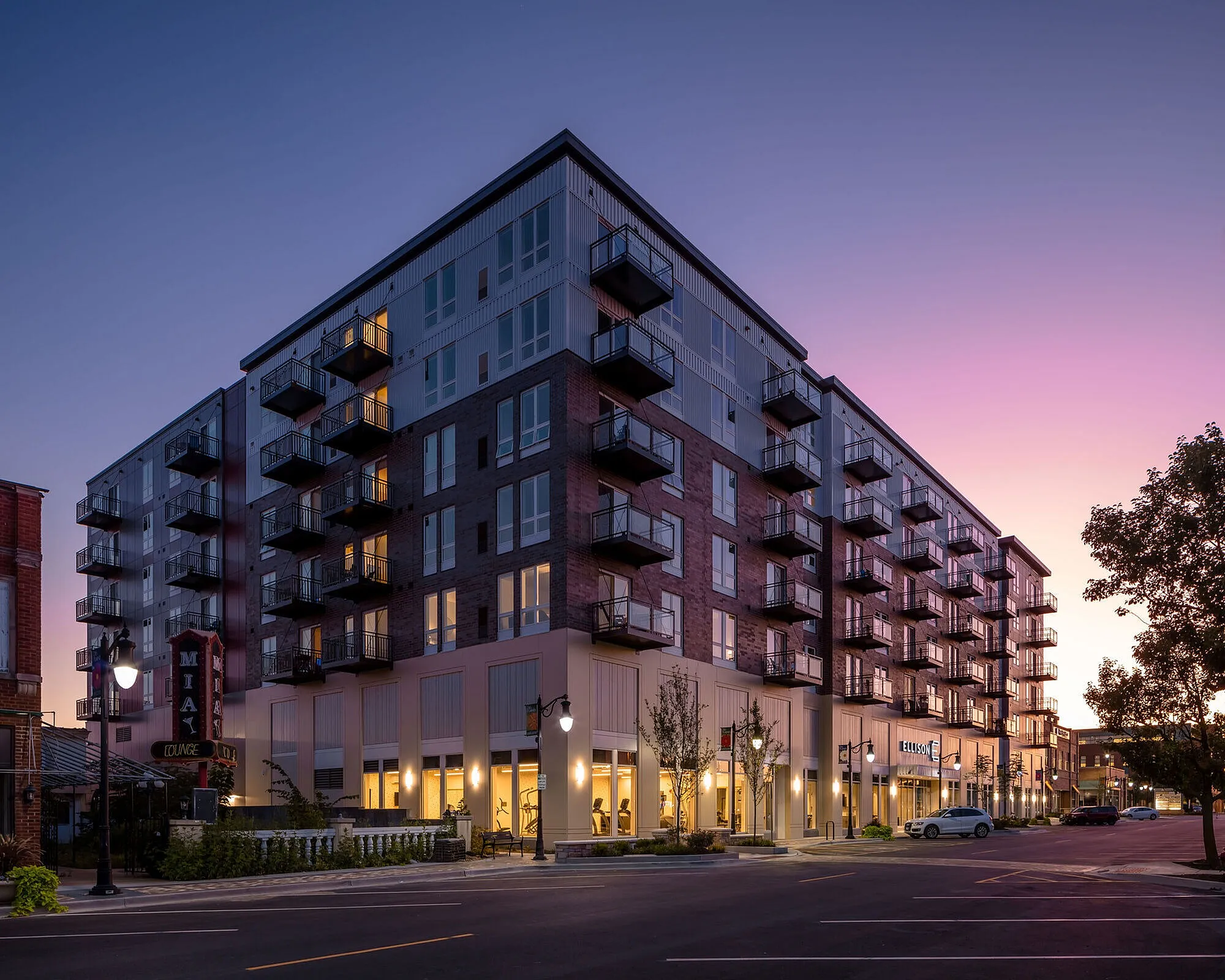 Modern apartment building at dusk with elegant balconies, warm lighting, and a vibrant urban atmosphere.