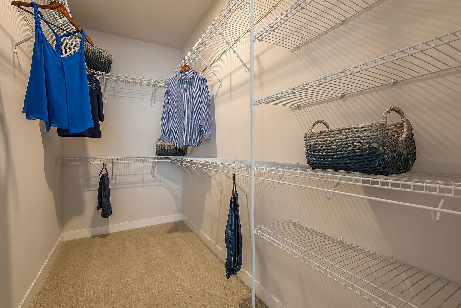 Spacious walk-in closet with elegant wire shelving and stylish wicker baskets, offering ample storage space.