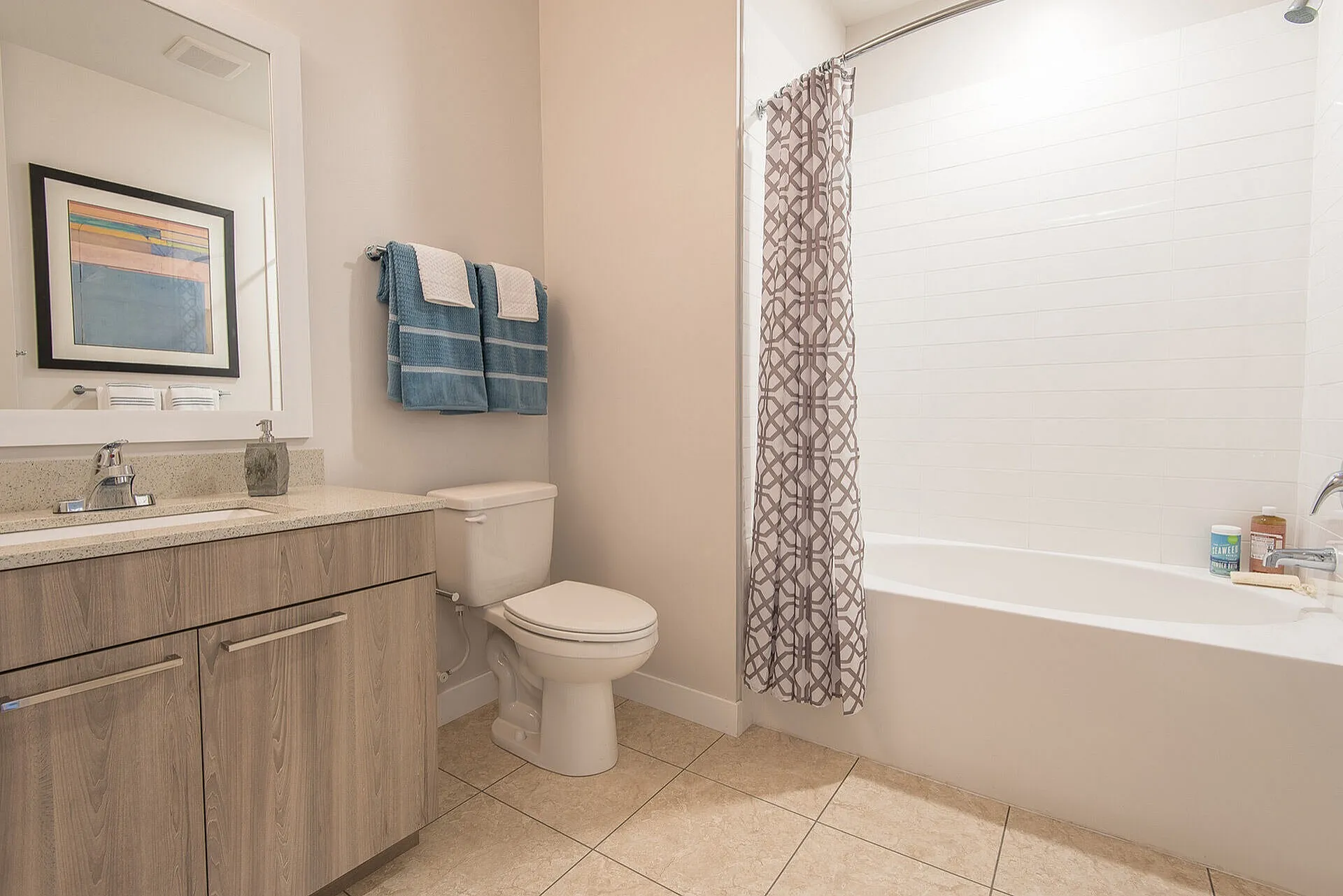 Modern bathroom featuring elegant wood cabinetry, stylish tile flooring, and a soothing bathtub with a patterned shower curtain.