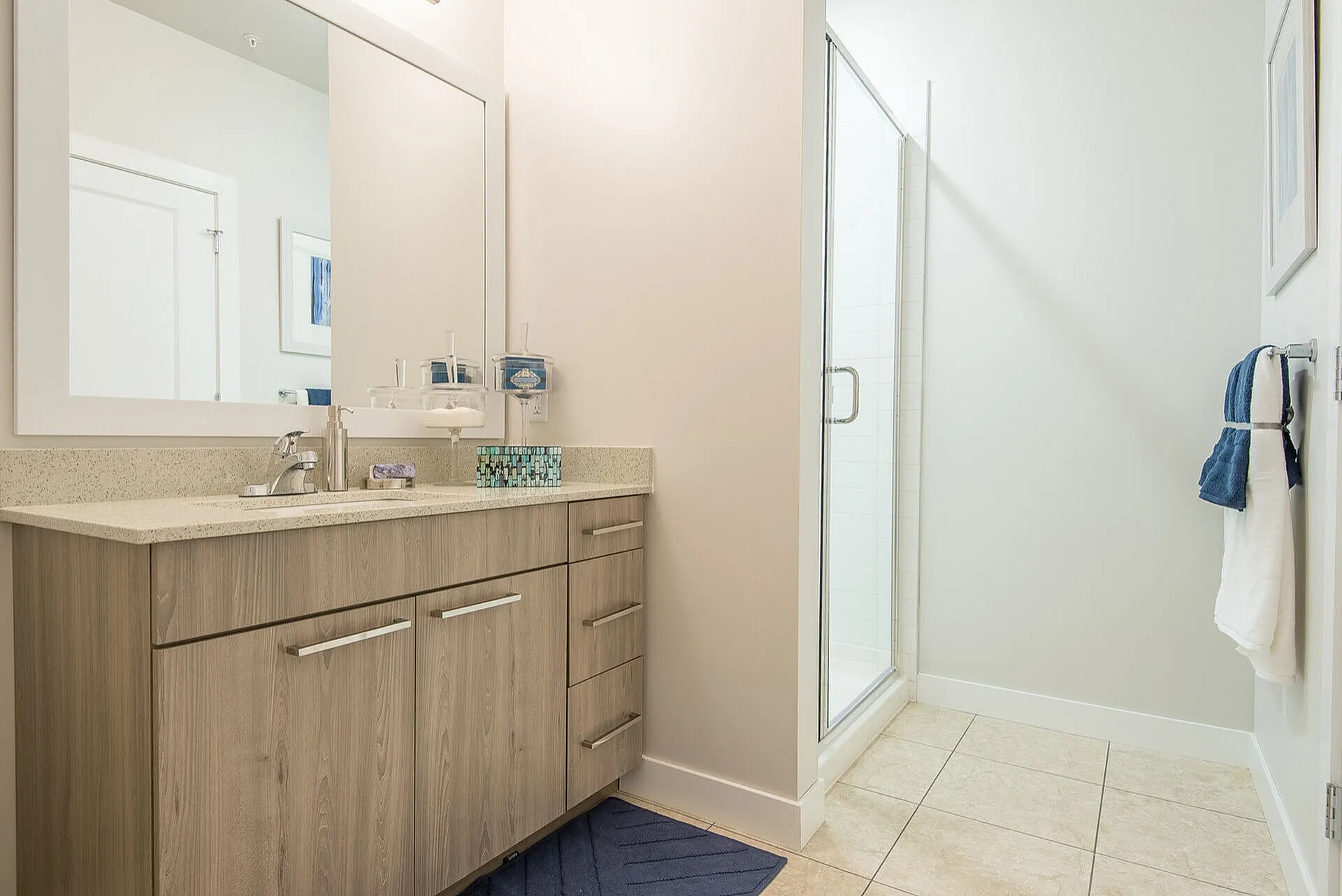 Elegantly designed bathroom featuring a sleek vanity with ample storage, a large mirror, and a modern glass shower.