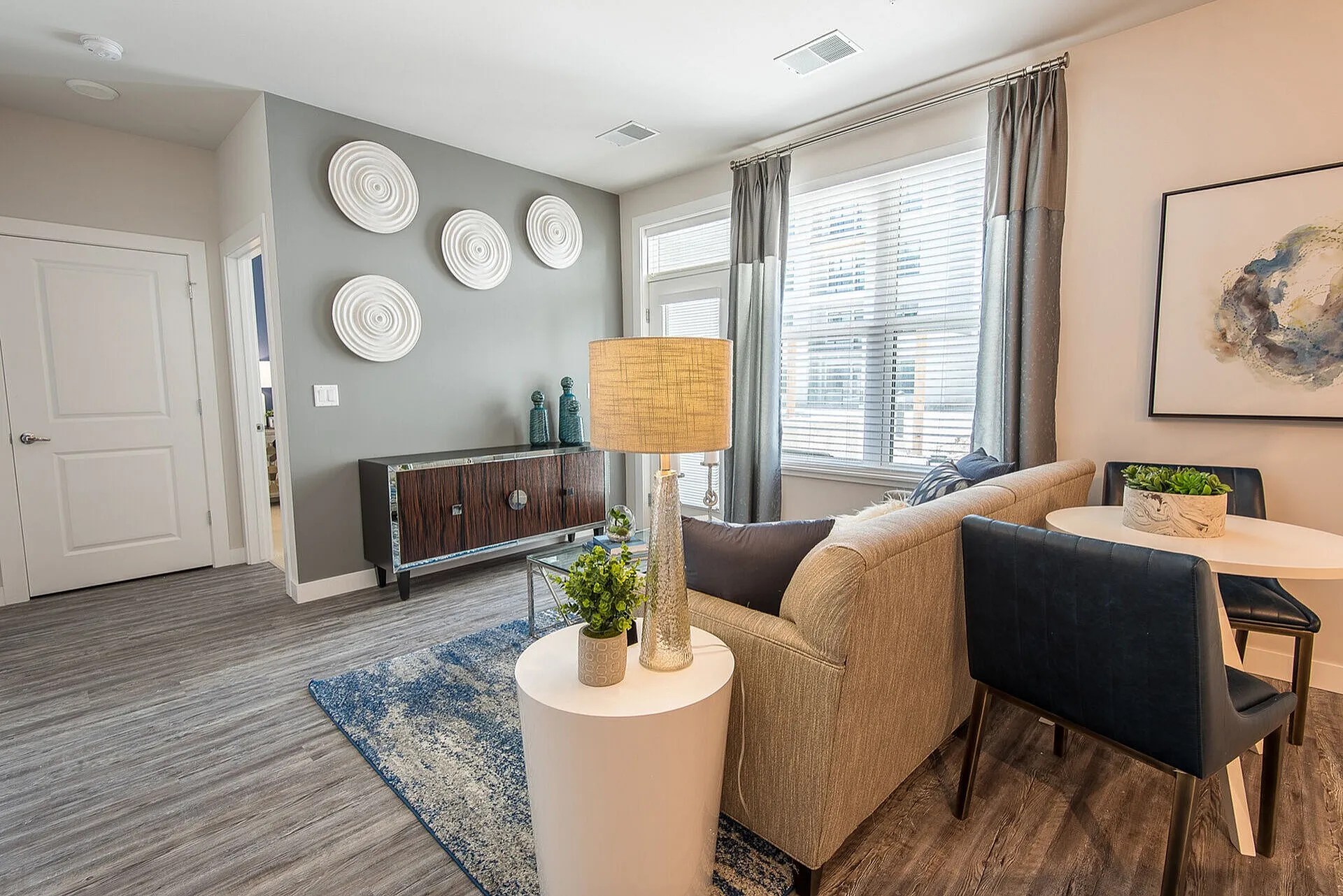 Chic living room with modern decor, featuring elegant wall art, a plush sofa, and abundant natural light through large windows.