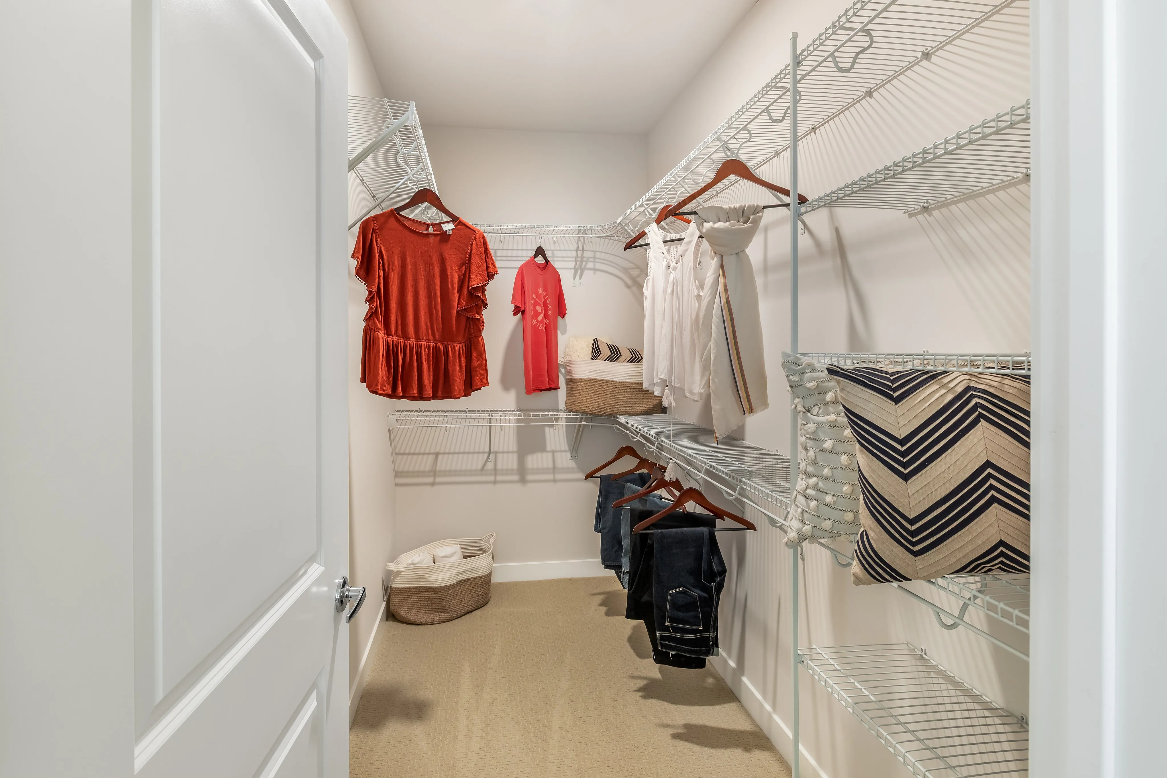 Spacious walk-in closet with organized shelving, stylish clothing, and elegant decor accents.