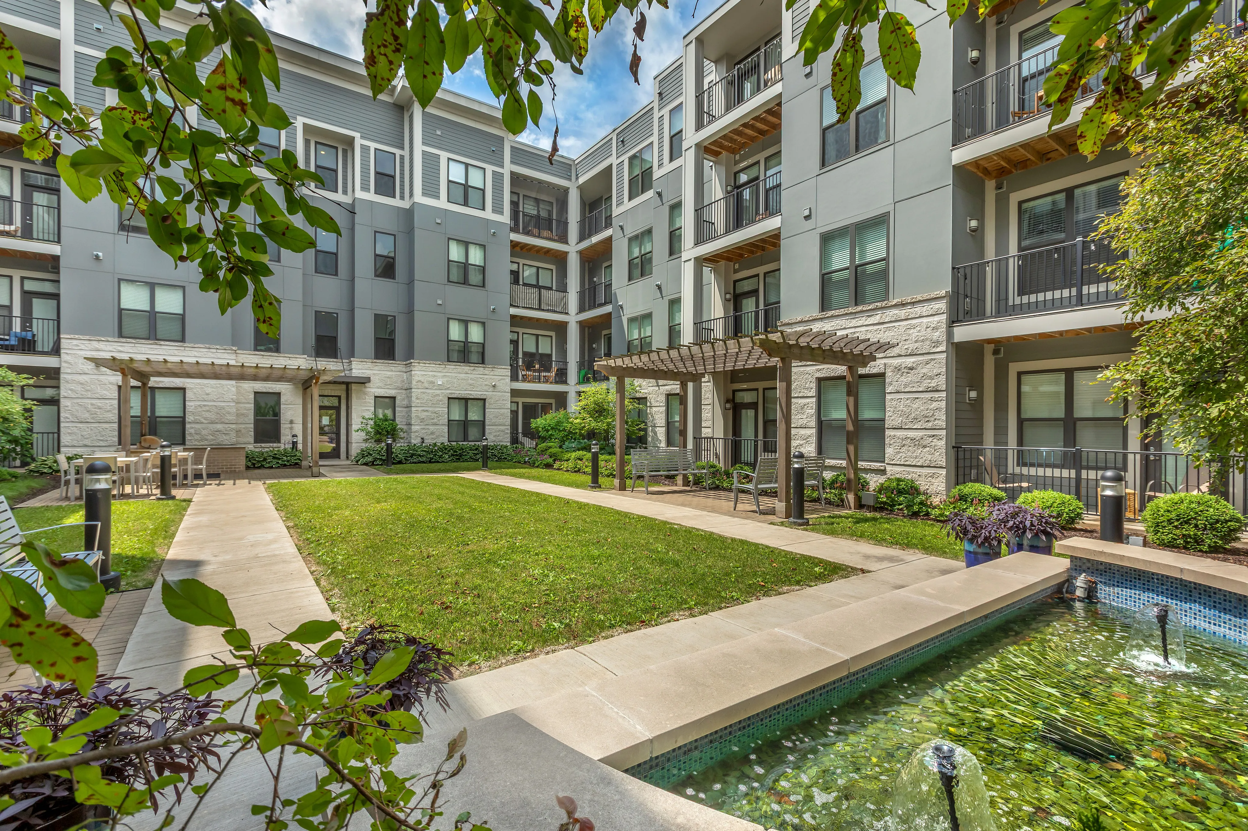 Charming apartment complex with modern architecture, lush courtyard, and tranquil water features.
