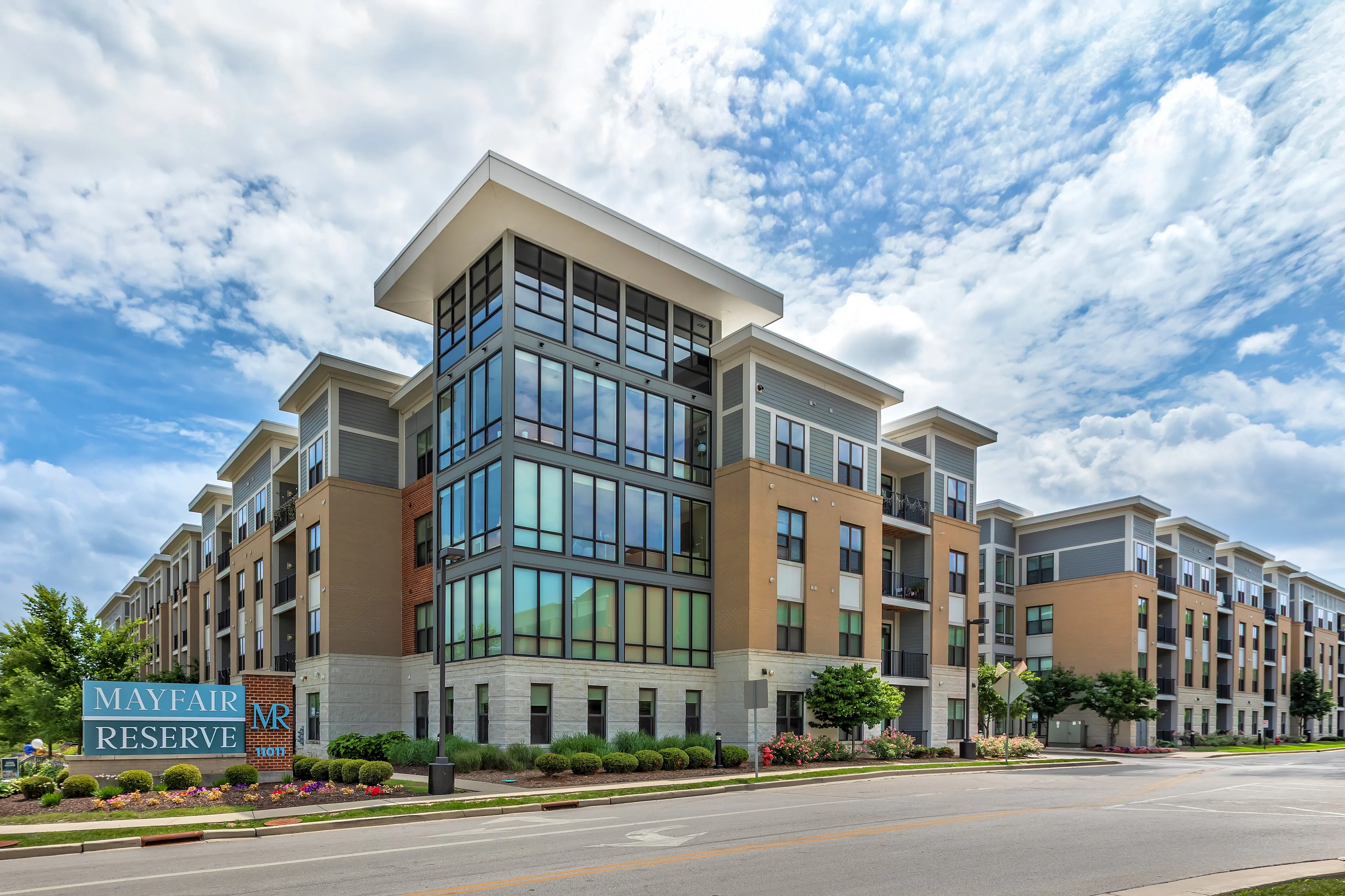 Impressive modern apartment complex with large windows and sleek architectural design under a picturesque sky.
