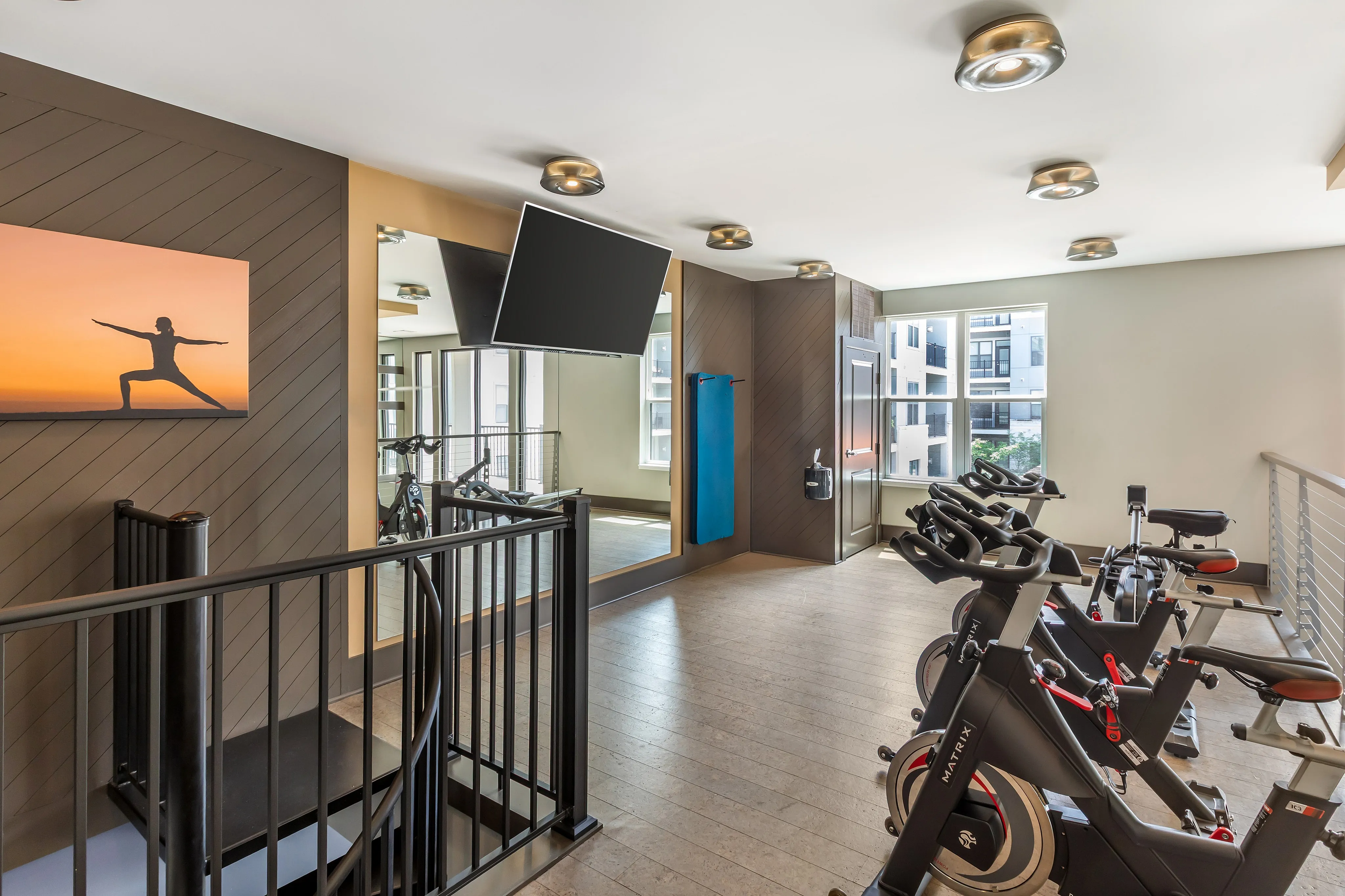 Modern apartment gym featuring sleek stationary bikes, large mirrors, and wall art for an energizing workout experience.