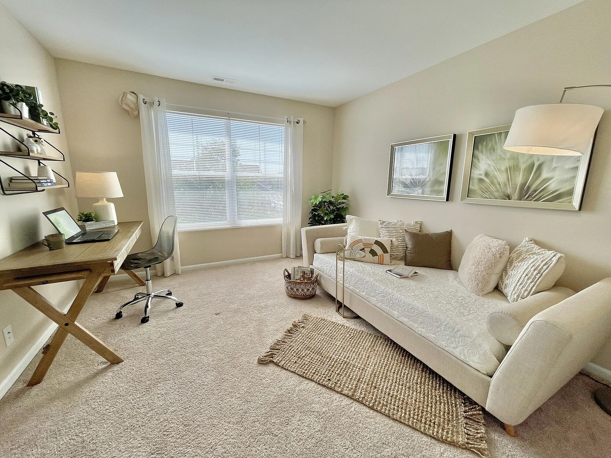 Elegant home office with natural lighting, featuring a cozy beige couch, plush pillows, and a wooden desk with decor accents.