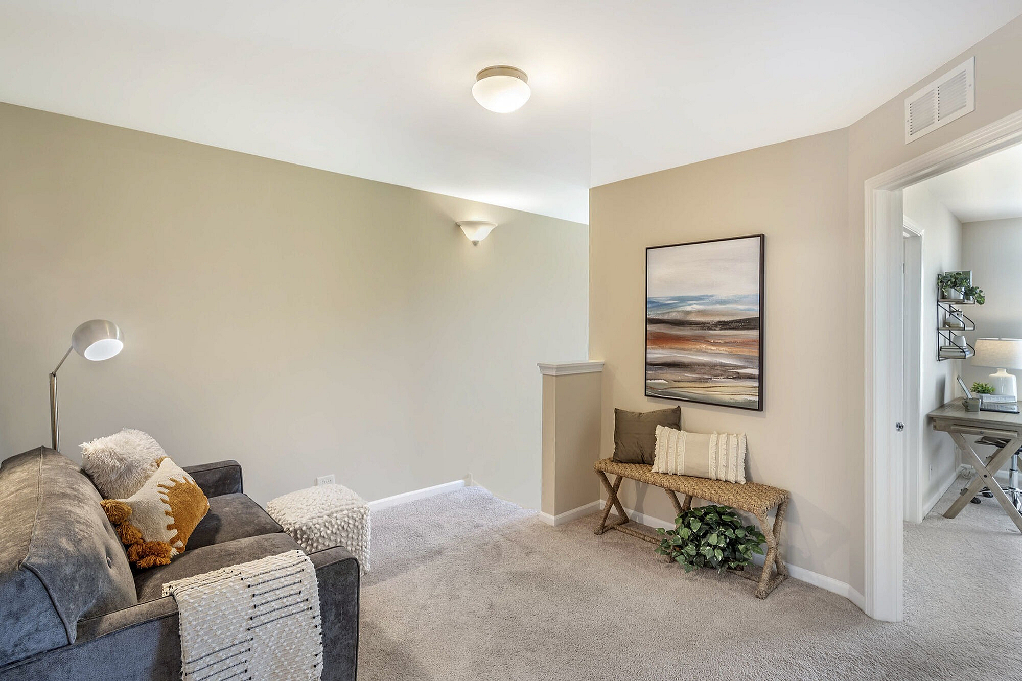 Chic apartment interior featuring a cozy alcove with a plush gray sofa, modern artwork, and soft lighting.