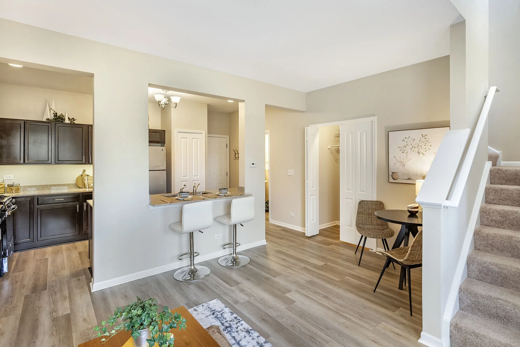 Modern open-concept apartment with sleek kitchen, cozy breakfast bar, and inviting dining nook, featuring elegant flooring and stylish decor.
