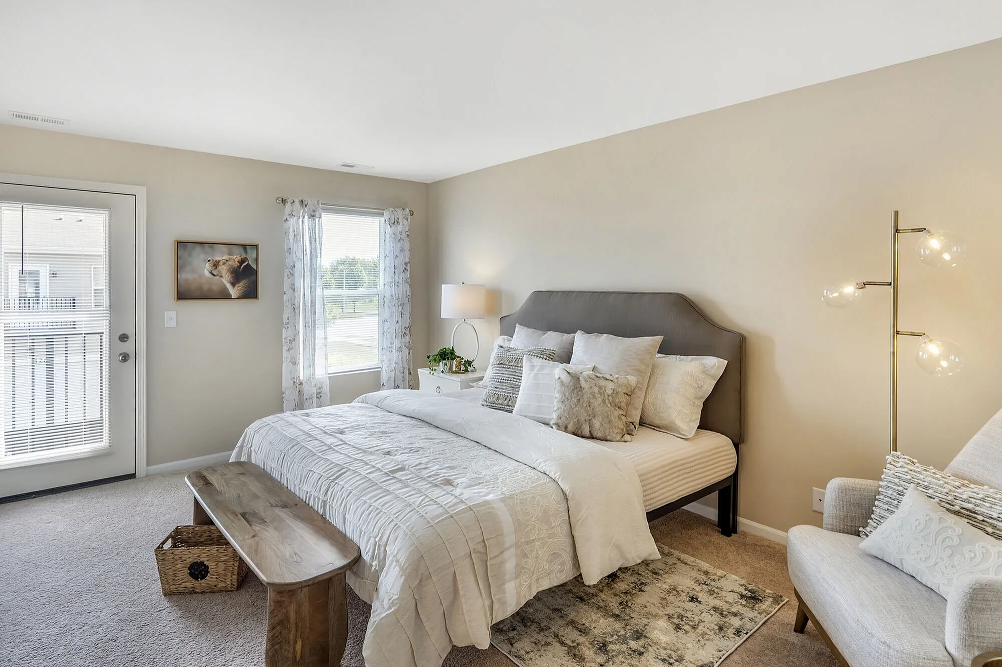 Bright and inviting bedroom featuring a plush bed with elegant pillows, natural light through large windows, and stylish decor creating a tranquil ambiance.
