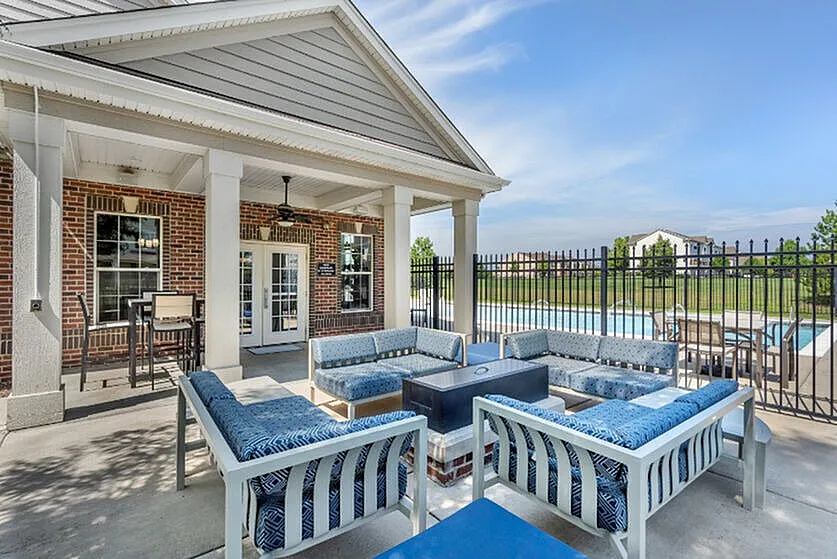 Charming outdoor patio area with elegant seating and a modern fire pit overlooking a sparkling pool, perfect for relaxing and entertaining.