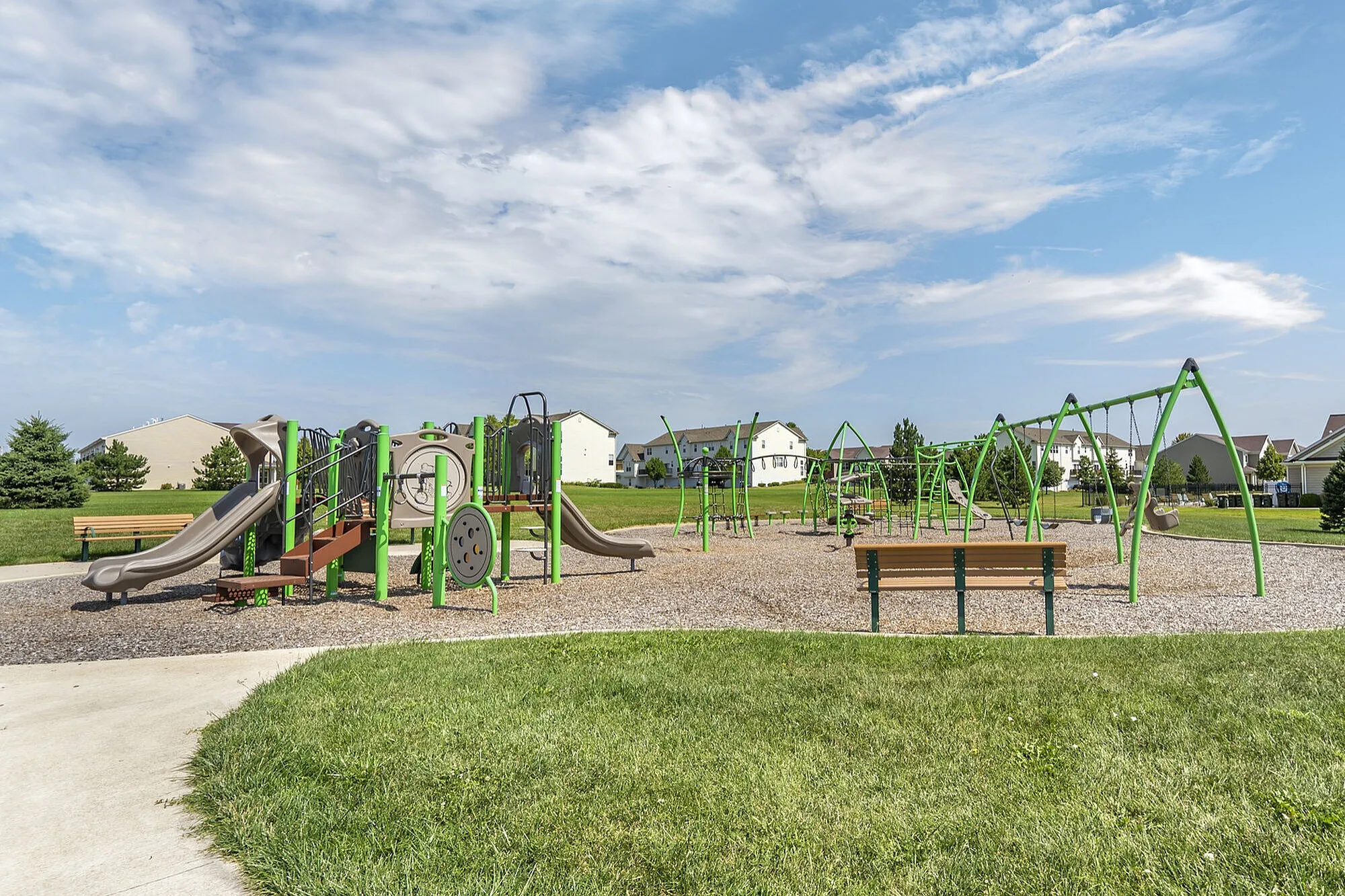 Inviting community playground featuring modern green and brown play equipment, set against a backdrop of a beautifully maintained neighborhood, perfect for family fun.