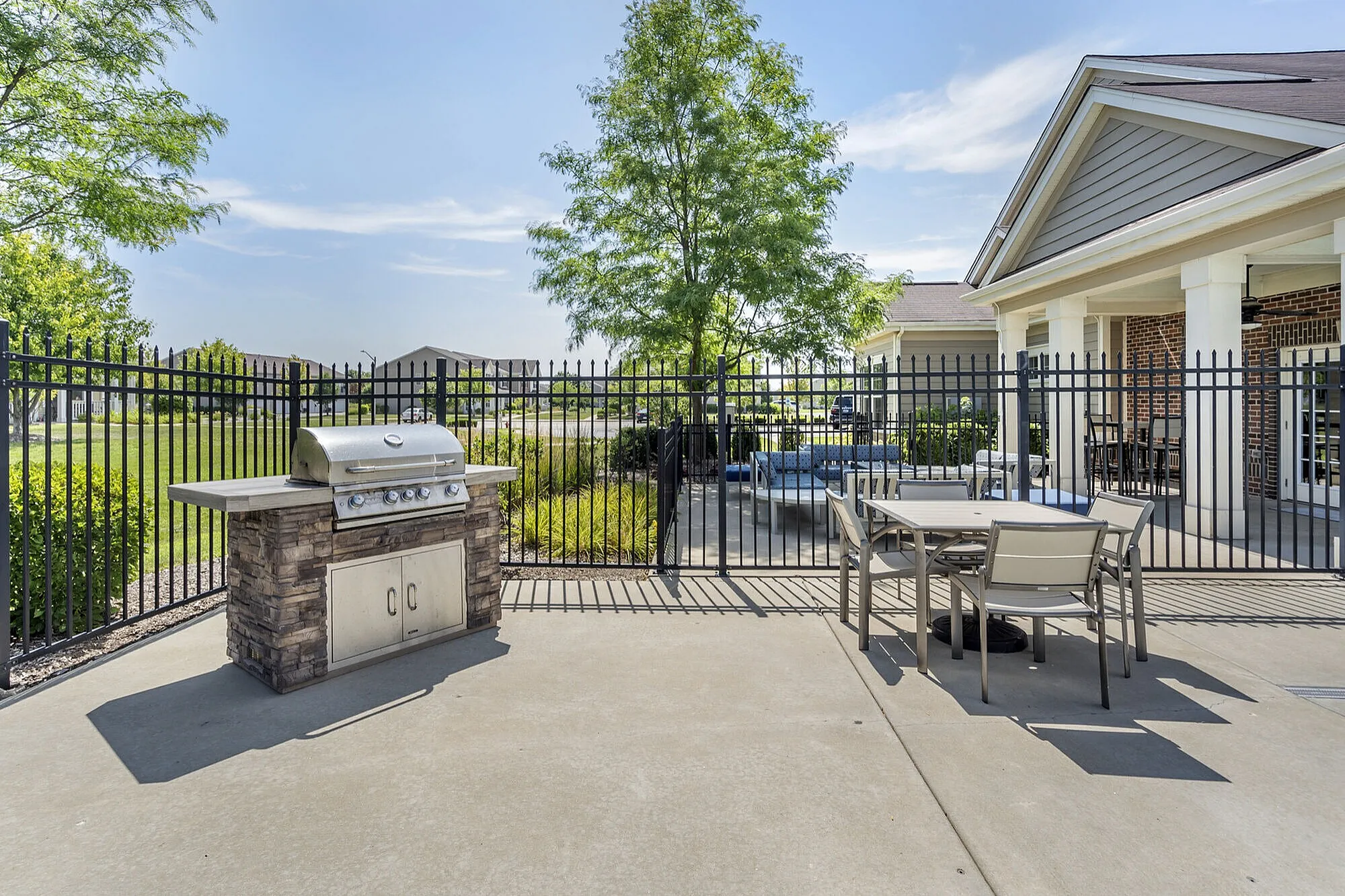 Charming outdoor patio with a modern grill, dining set, and lush garden view, perfect for entertaining.