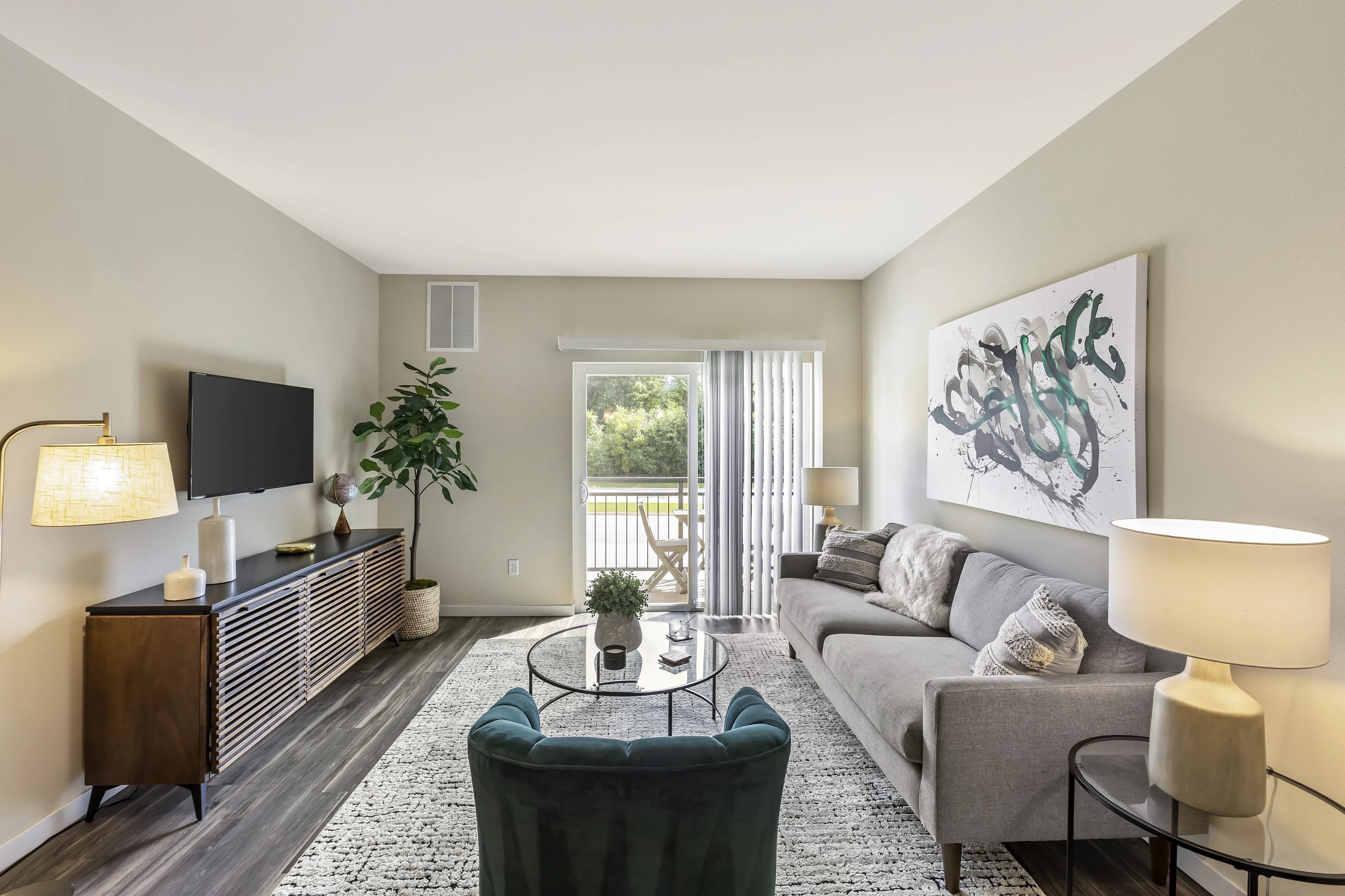 Chic living room with modern furniture, a cozy gray sofa, stylish decor, and a scenic balcony view.