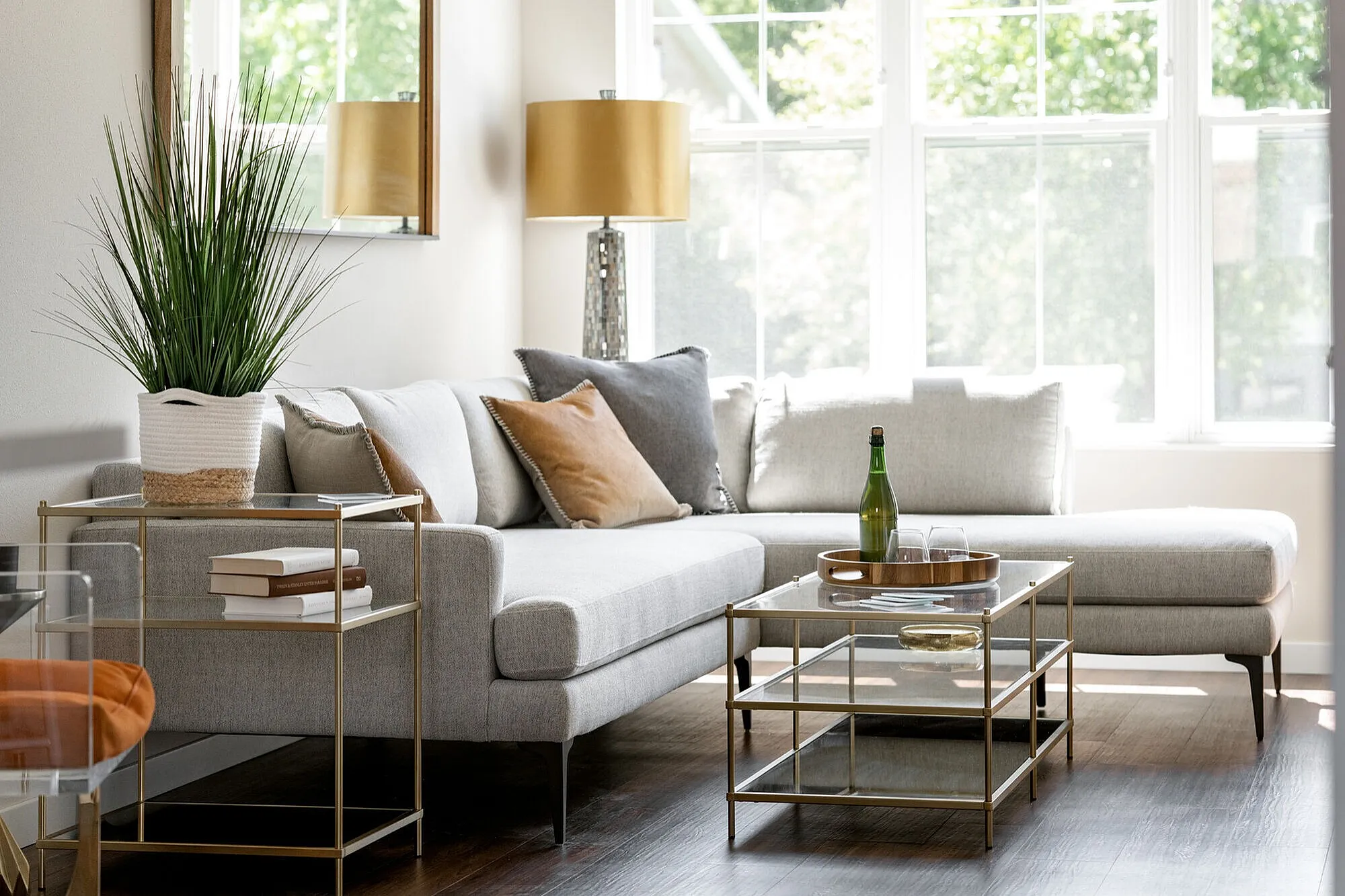 Inviting living room with a chic gray sectional sofa, plush cushions, and elegant glass tables, bathed in natural light.