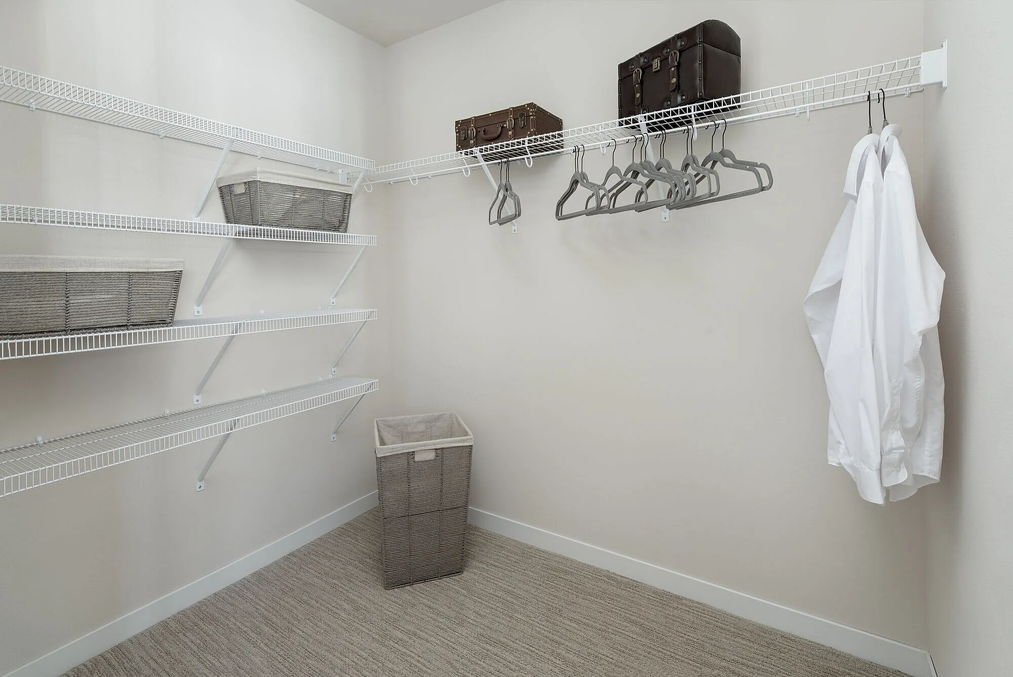 Spacious walk-in closet with multiple wire shelves, elegant hangers, and storage baskets, perfect for organized and stylish living.