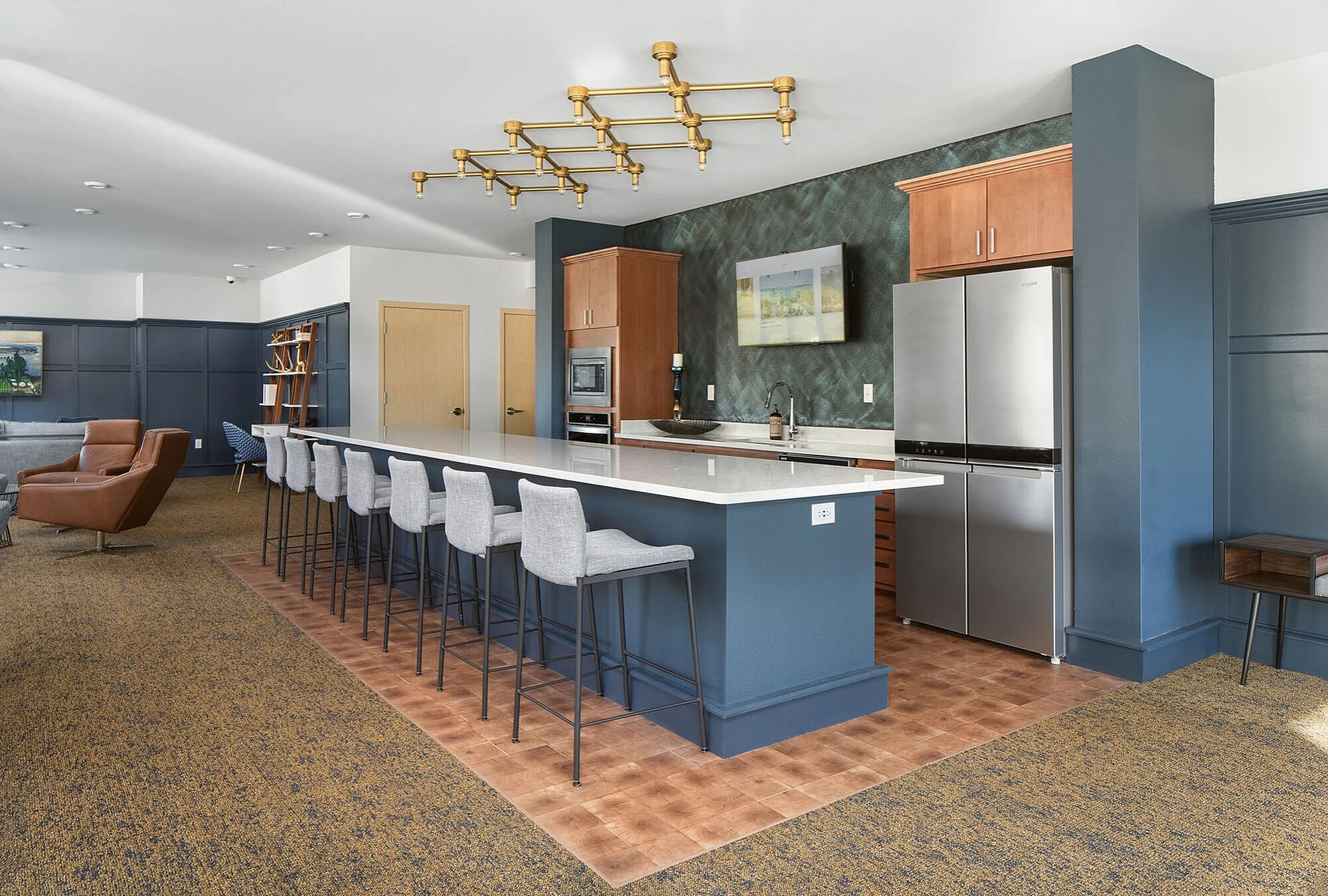 Elegant open kitchen with a sleek island and modern barstools, featuring stainless steel appliances and stylish lighting accents.