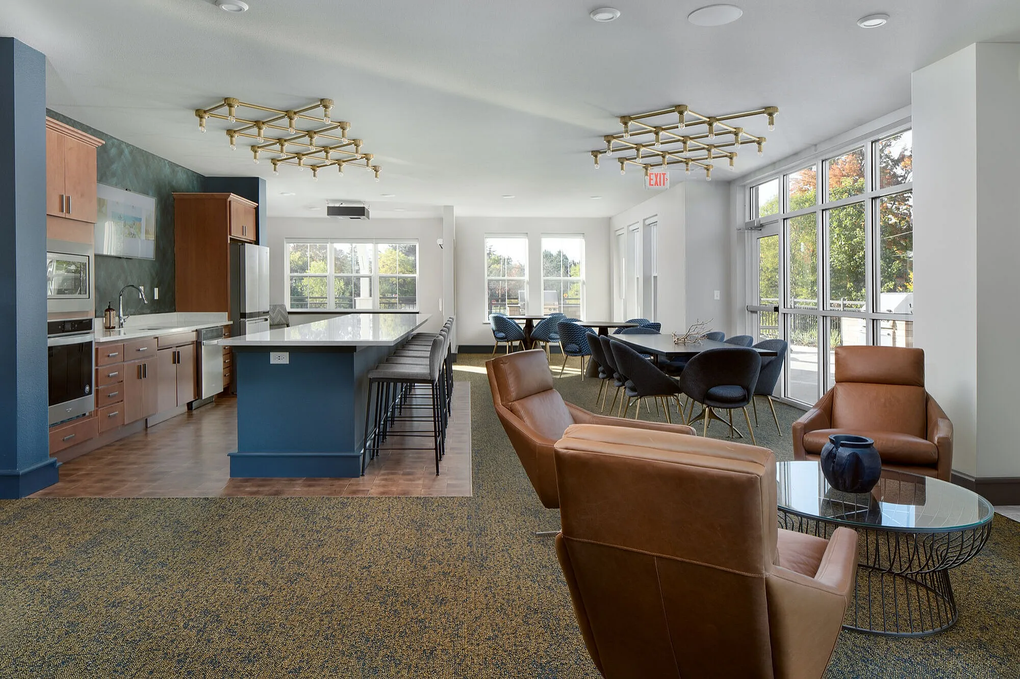 Modern communal living space with a spacious kitchen, sleek island seating, and a chic dining area featuring large windows for natural light.