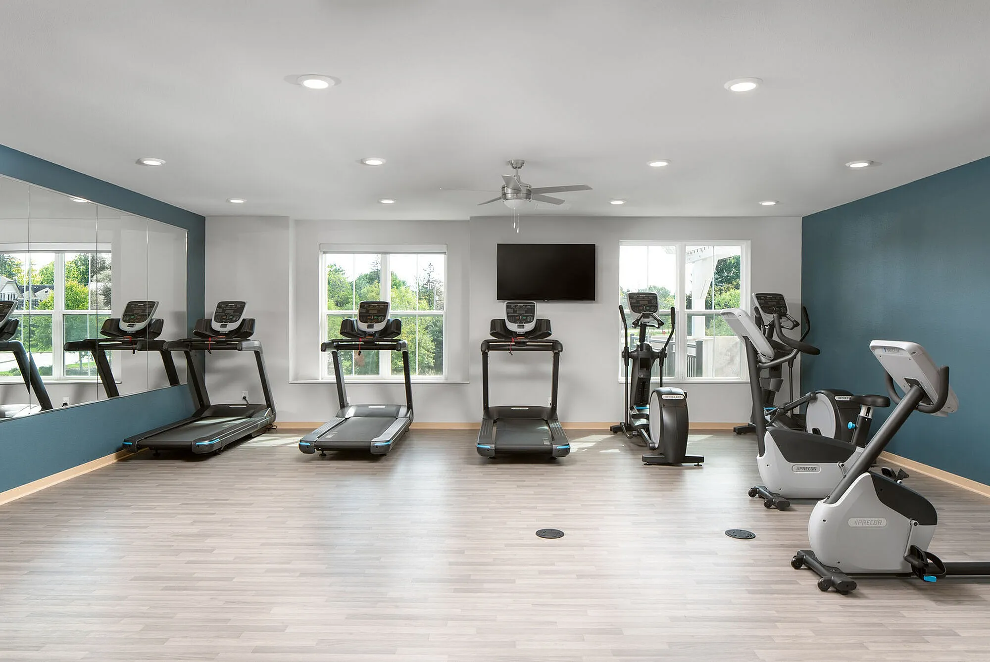 Modern fitness center with state-of-the-art treadmills, exercise bikes, and a scenic view through large windows.