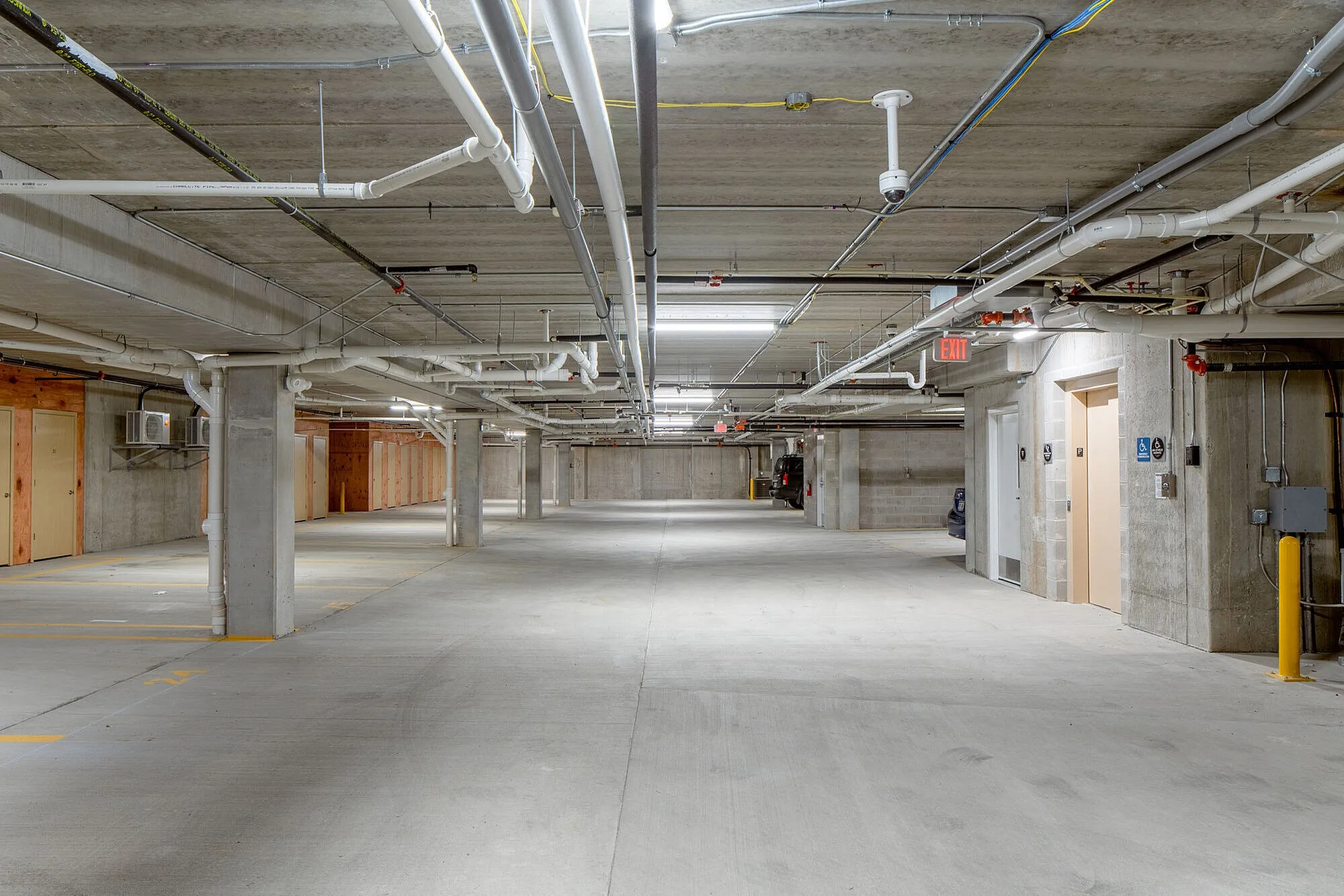 Spacious and well-lit underground parking garage with convenient access to elevators and ample space for vehicles.
