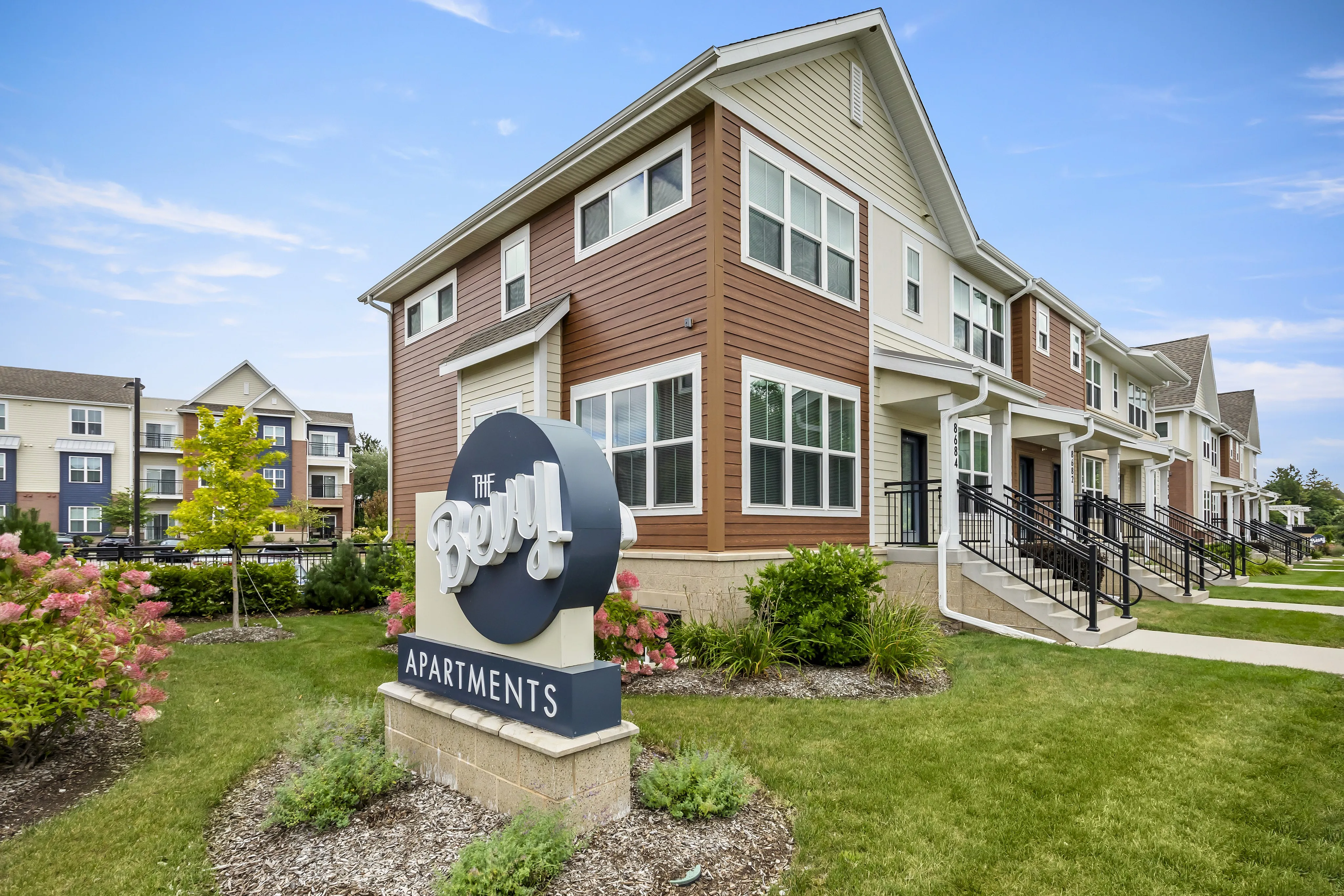 Charming townhouse-style apartments at The Bevy with lush landscaping and inviting exterior, ideal for modern living.