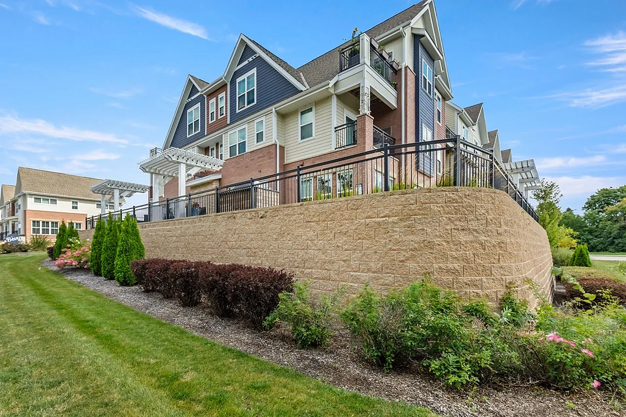 Elegant multi-story apartment building featuring modern architecture with charming gables, lush landscaping, and spacious outdoor terraces.