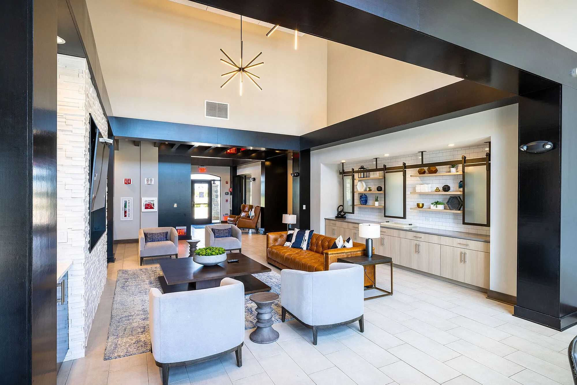 Elegant apartment common area with sleek modern design, featuring plush seating, stylish lighting fixtures, and a contemporary bookshelf wall.