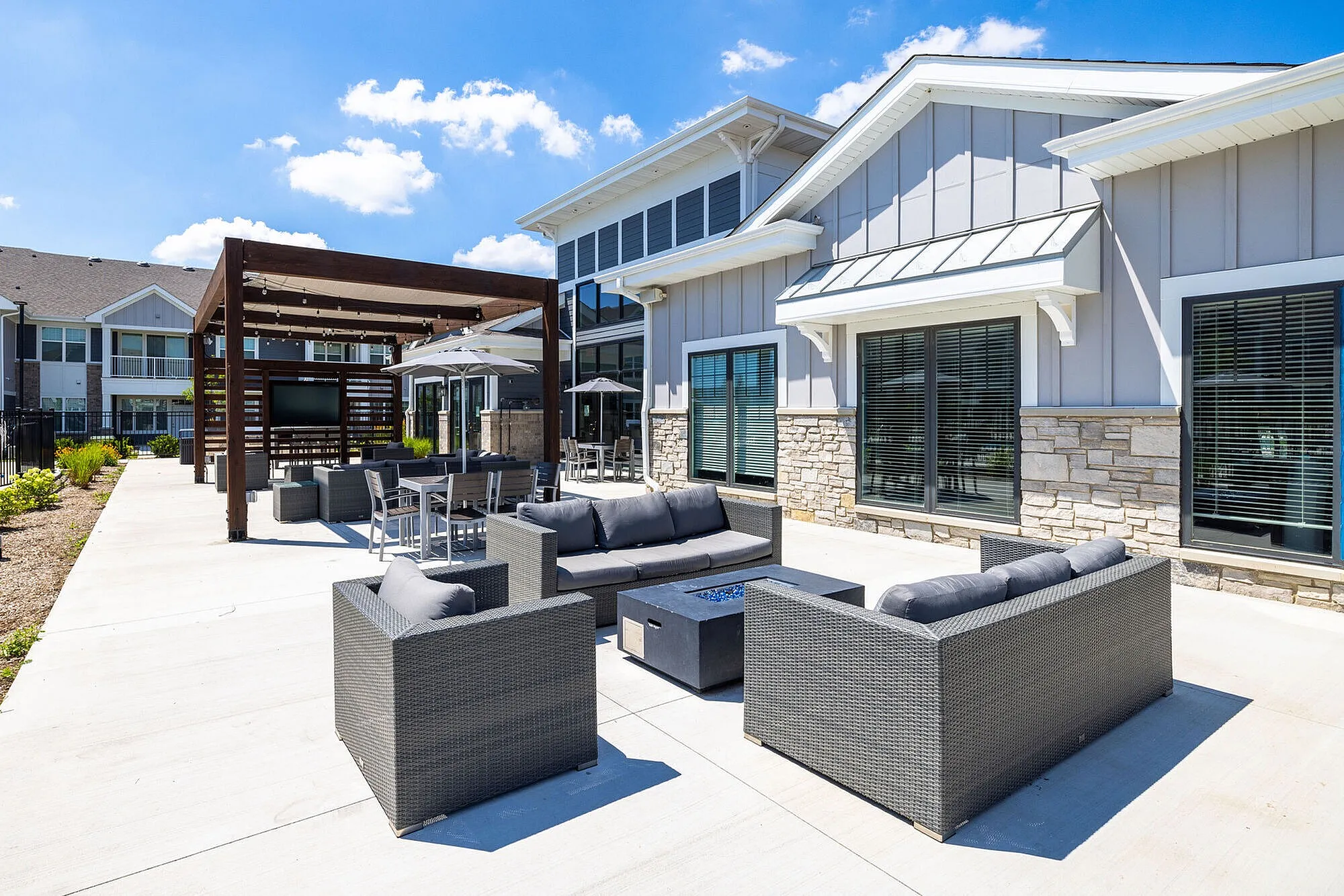 Chic modern patio with comfortable wicker seating and pergola, perfect for outdoor relaxation and entertainment.