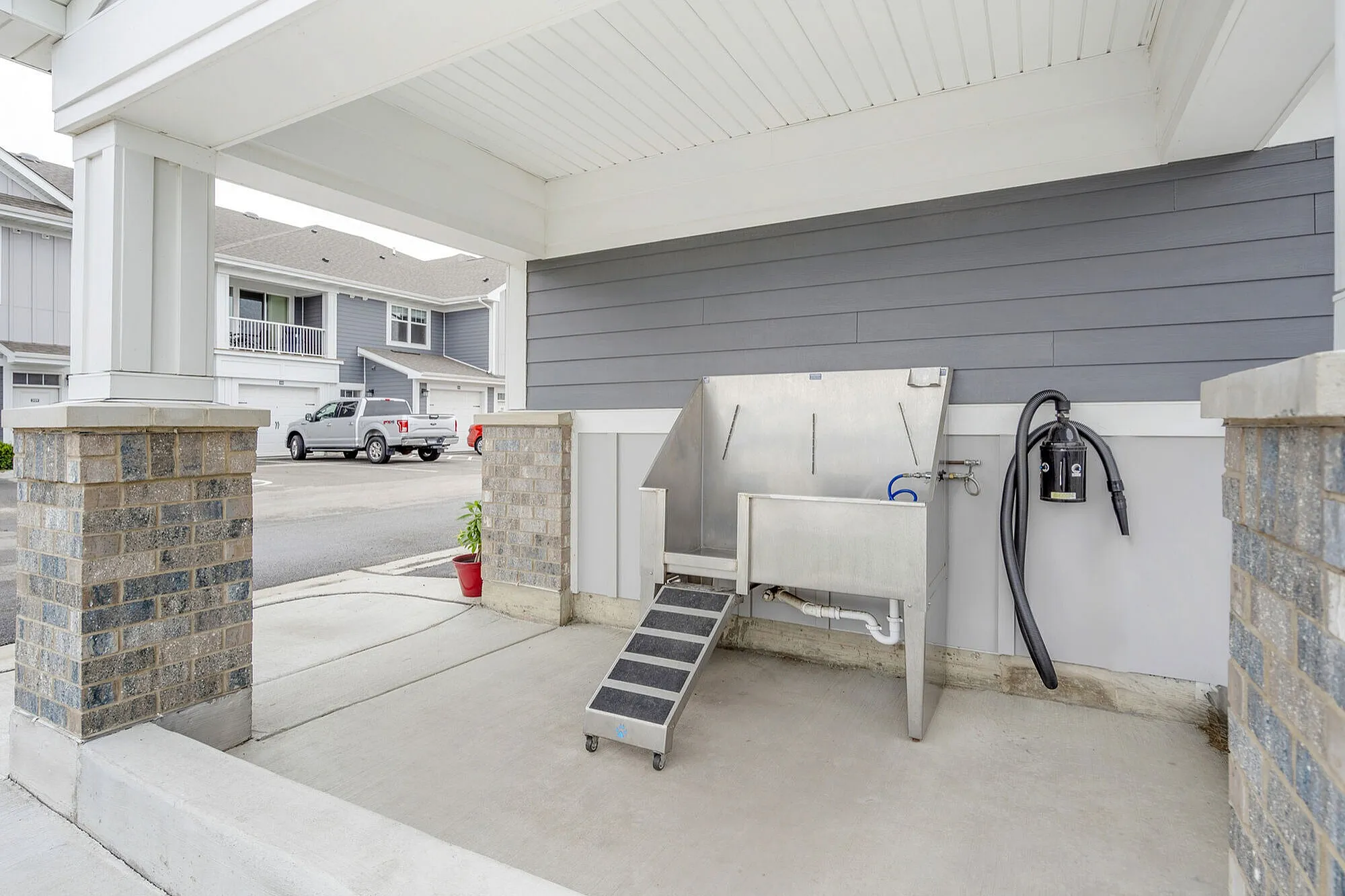 Chic outdoor area featuring a modern pet washing station with stylish brick pillars and ample driveway space.