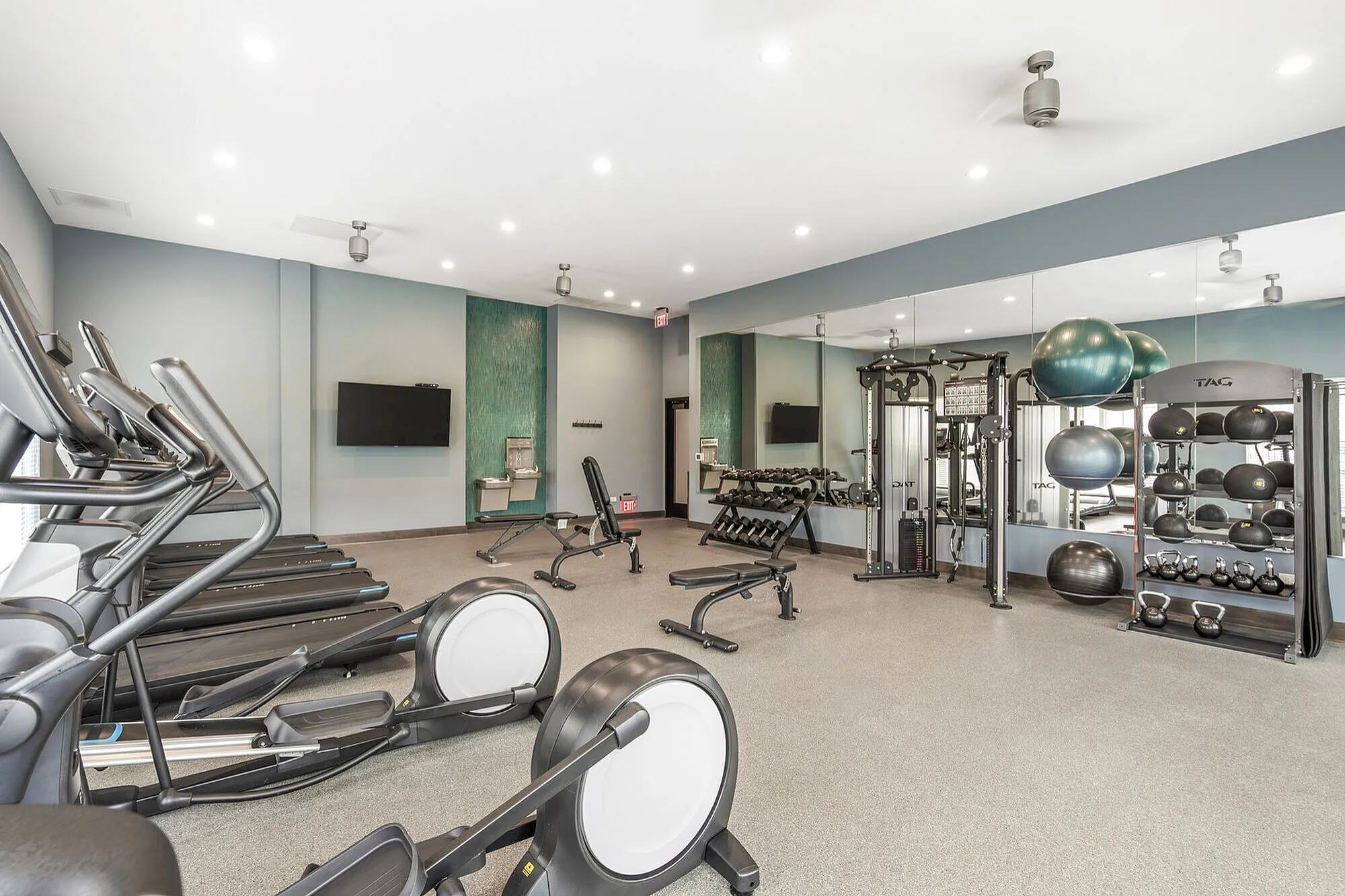 Spacious and modern fitness center equipped with treadmills, weights, and exercise balls, perfect for a complete workout.