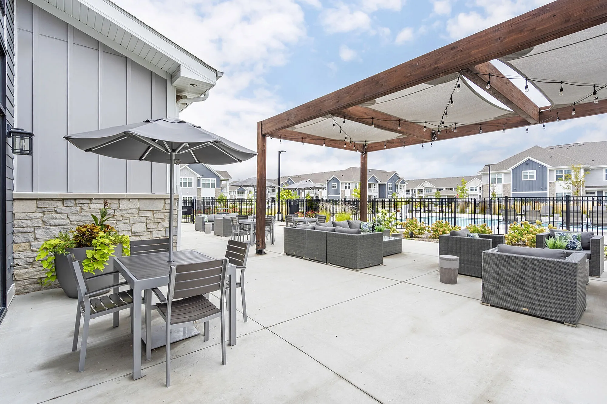 Chic outdoor patio area featuring stylish seating, a shaded dining set, and elegant pergola with string lights, perfect for relaxation and gatherings.