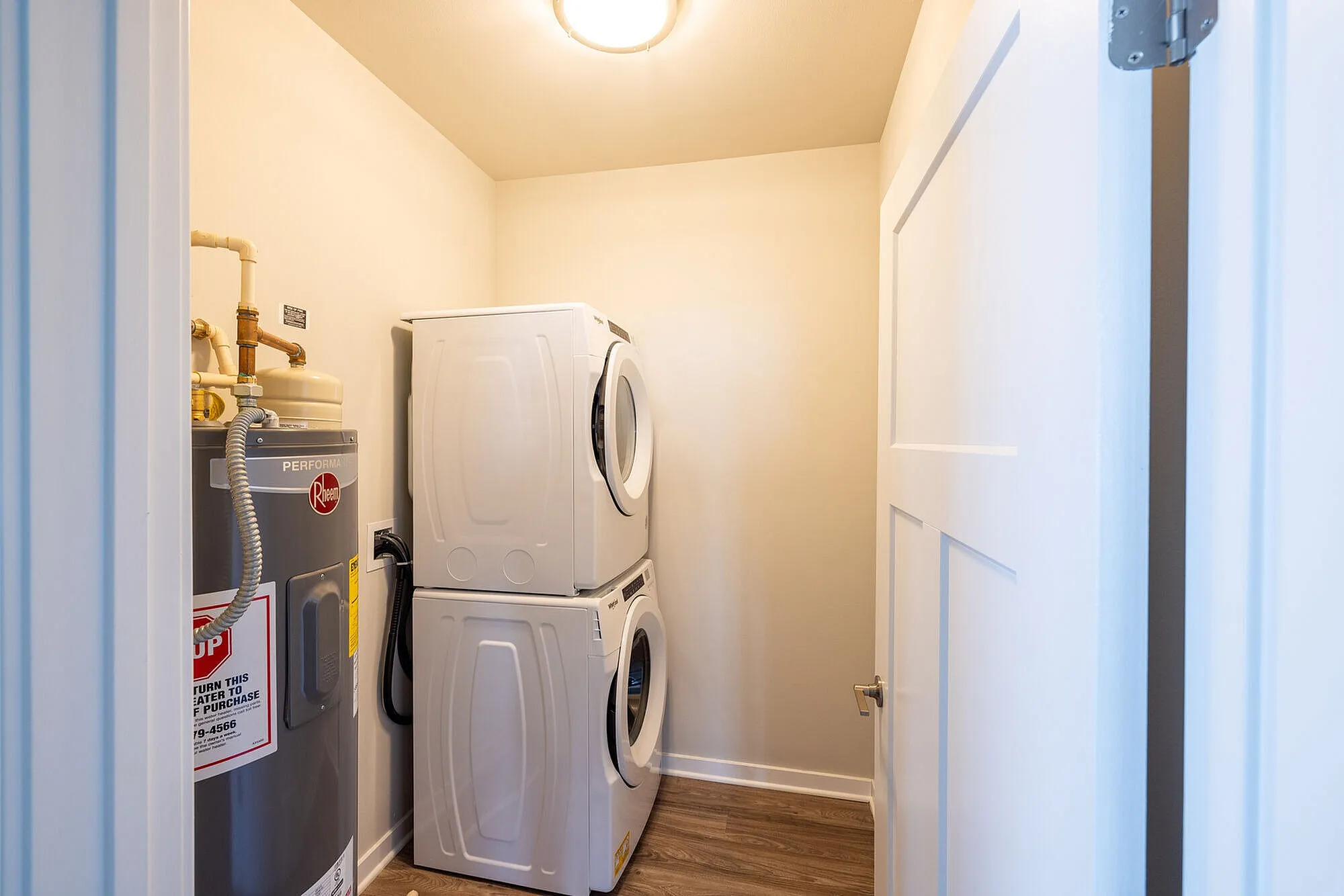 Bright laundry room with modern stacked washer and dryer, complemented by efficient water heater for convenience.