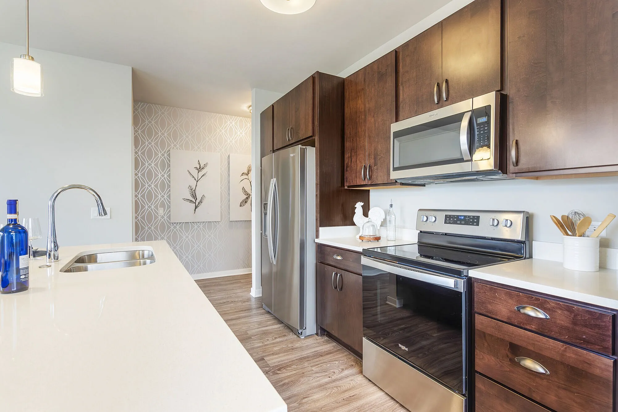 Sleek modern kitchen with stainless steel appliances, elegant dark wood cabinetry, and a polished white countertop.