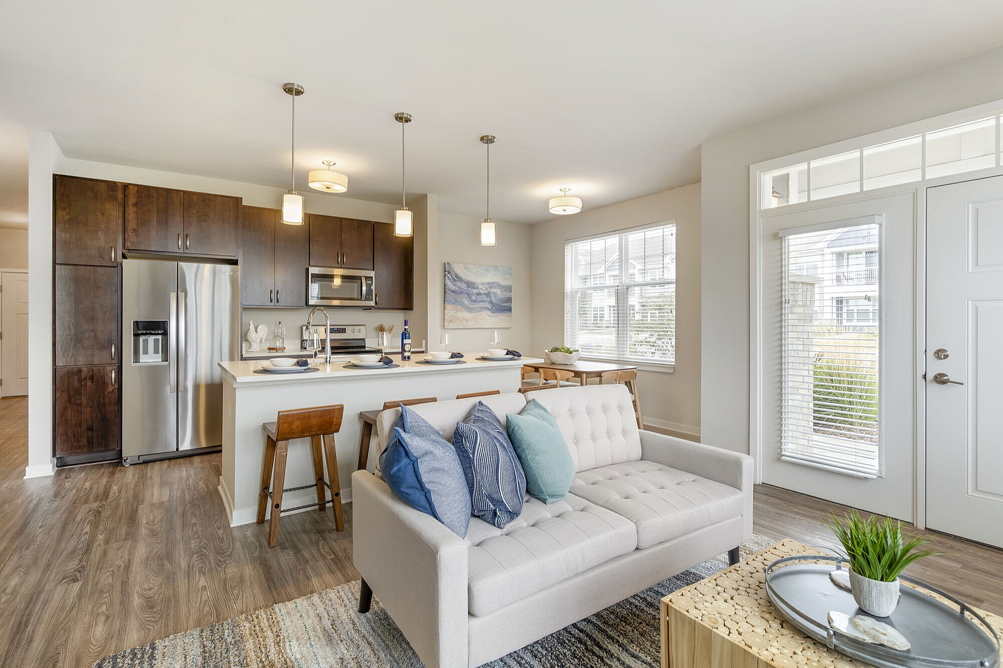 Bright open-concept living space with a sleek modern kitchen, cozy sofa, and large windows enhancing natural light.