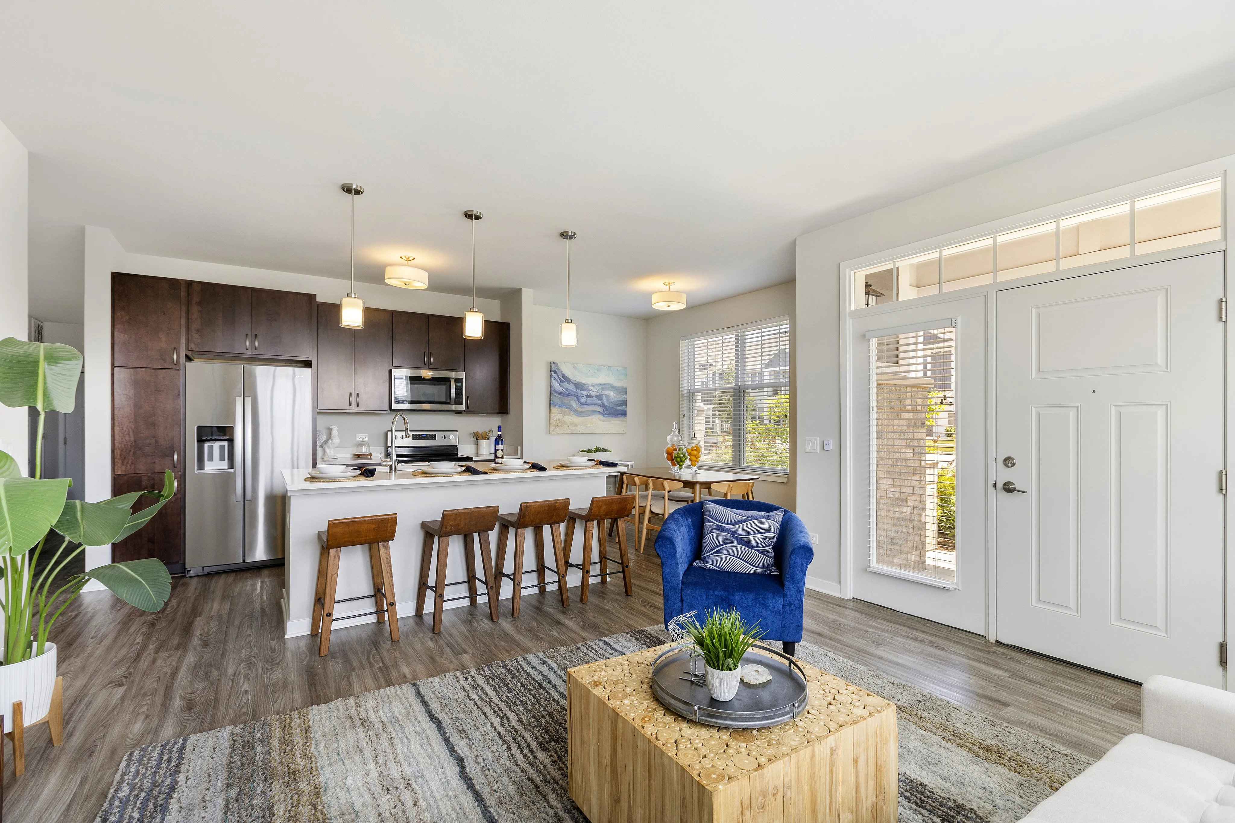Bright open-concept living space featuring a modern kitchen with a sleek island, stylish dining area, and cozy seating, illuminated by natural light.