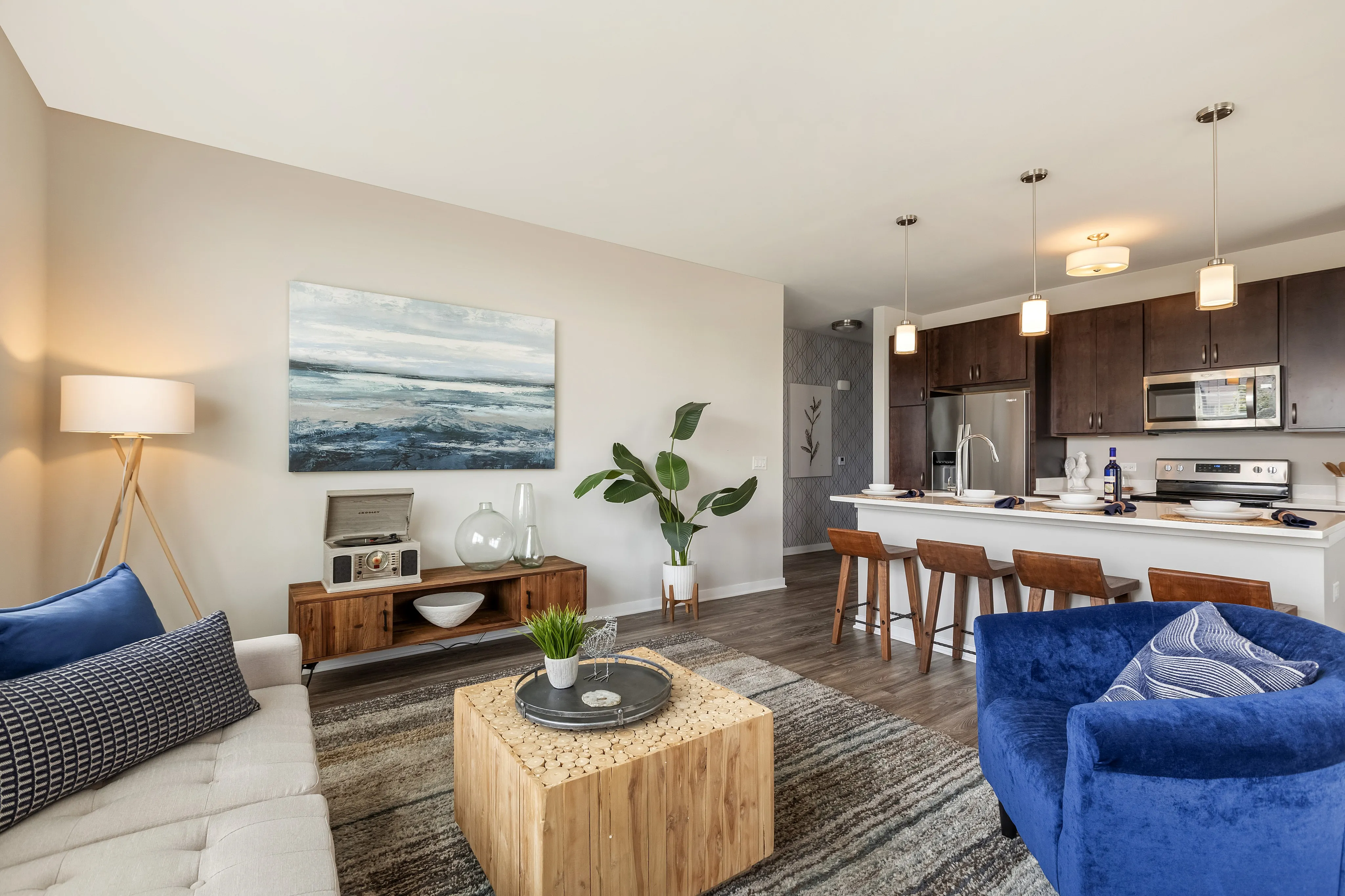 Modern living room and kitchen with open floor plan, featuring stylish furnishings, cozy seating, and elegant lighting.