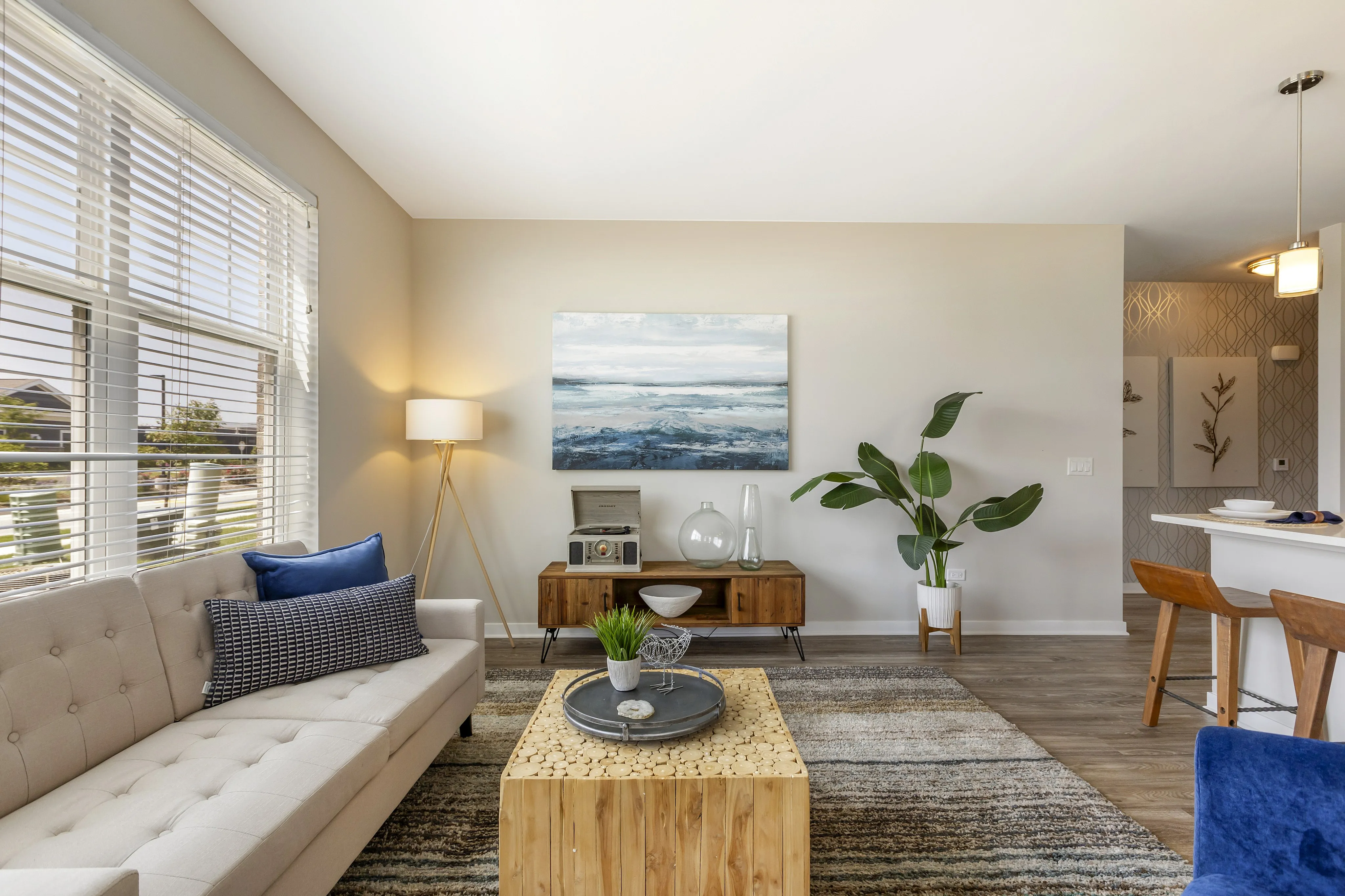 Modern living room with stylish decor, featuring a cozy beige sofa, vibrant artwork, and elegant wooden furniture.