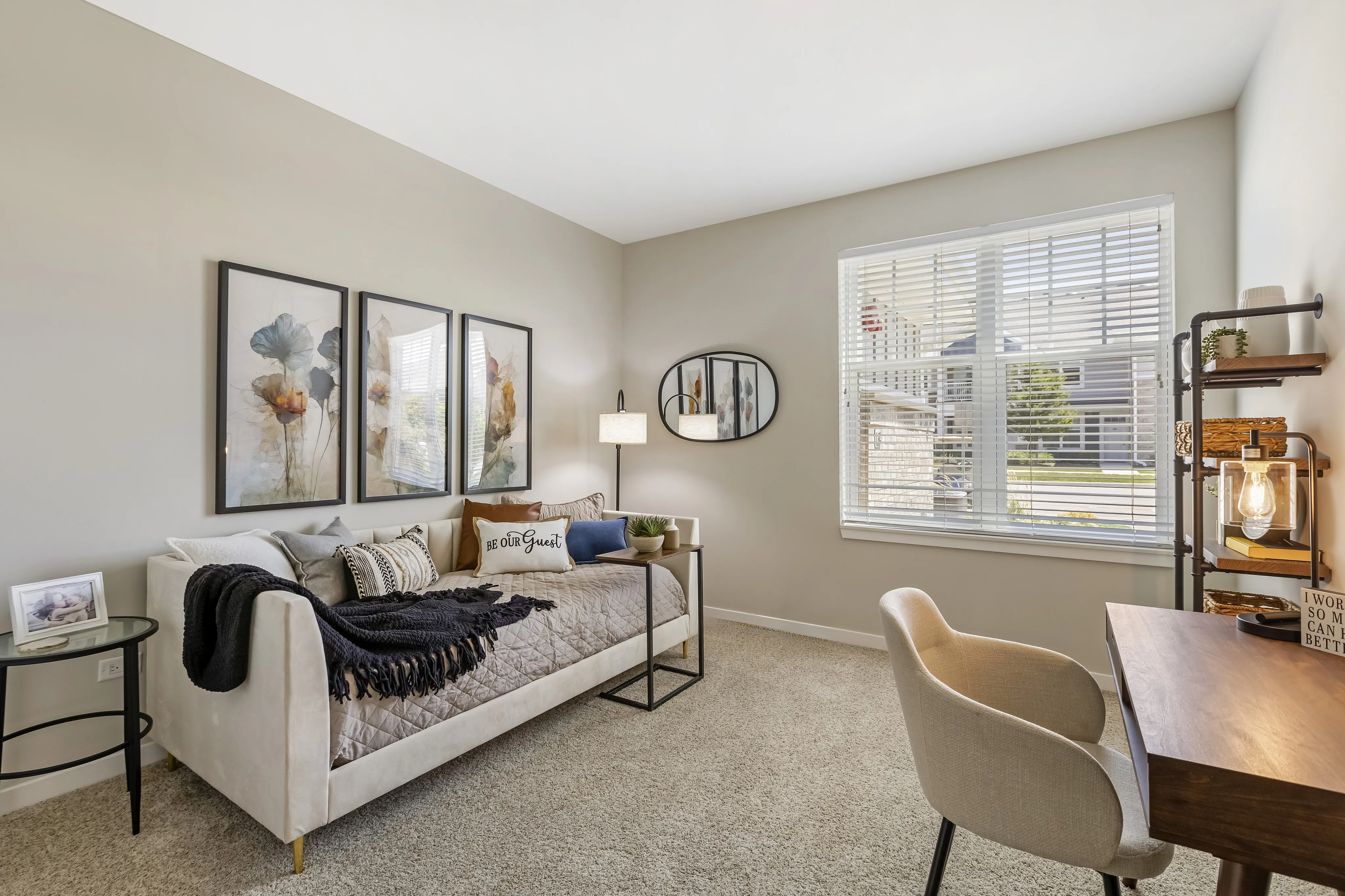Inviting home office with stylish decor, featuring a cozy daybed, soft lighting, and a spacious desk near a sunlit window.