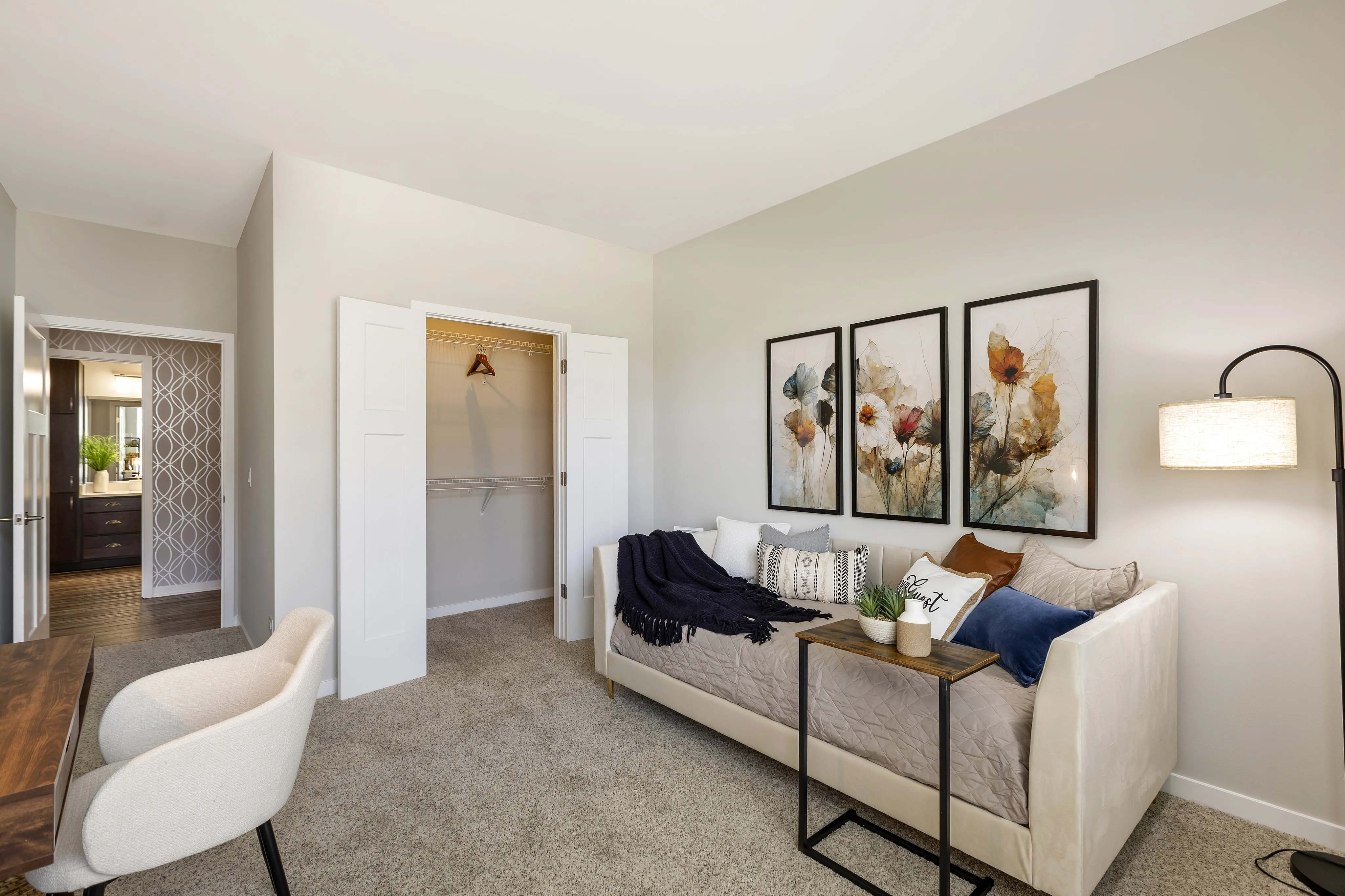 Chic and cozy bedroom with elegant decor, featuring a plush daybed, stylish artwork, and a spacious walk-in closet. Natural light fills the room through a modern floor lamp, perfect for relaxation.