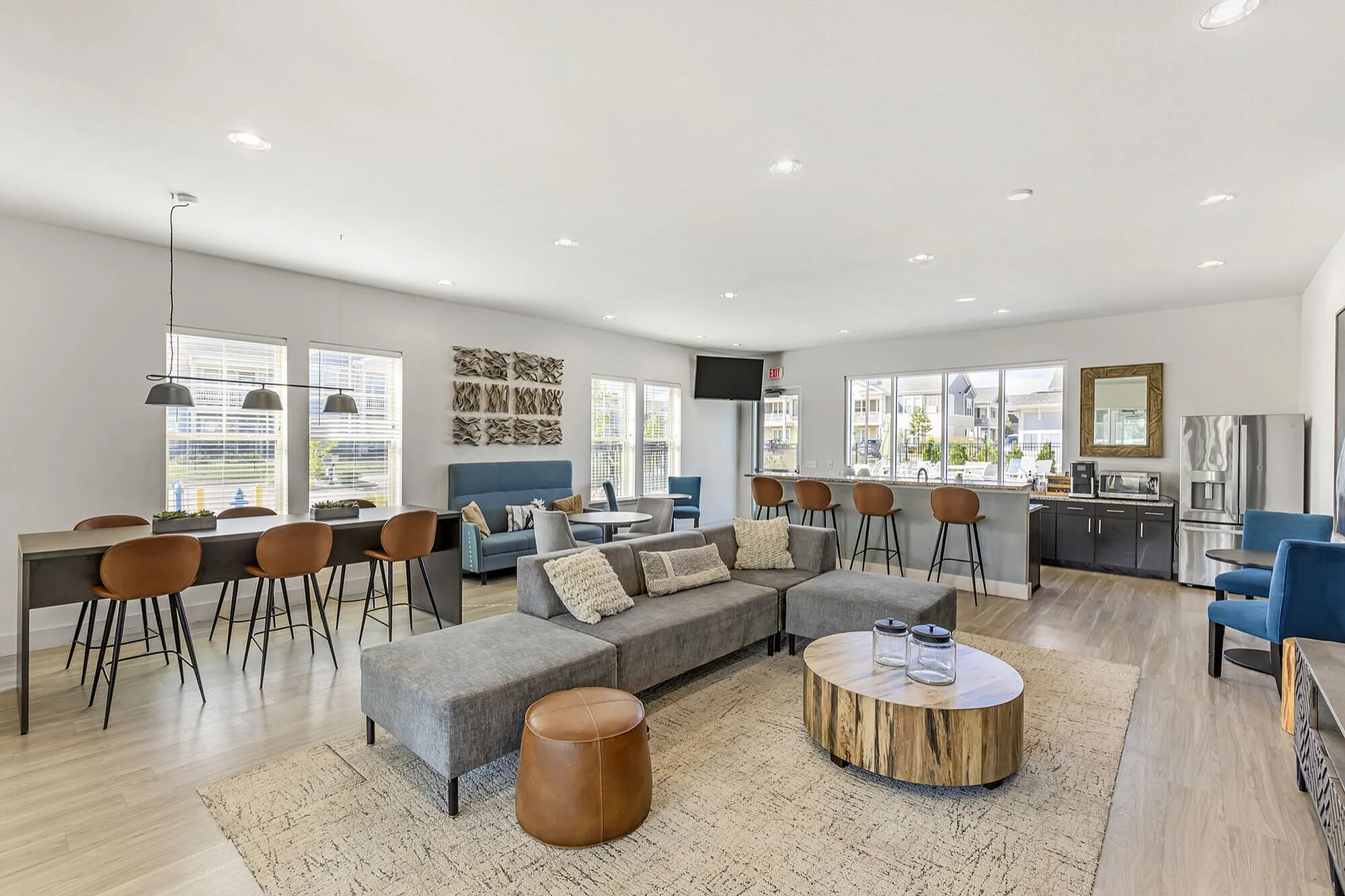 Modern and inviting common area with stylish seating, large windows, and a well-equipped kitchen space, perfect for social gatherings.